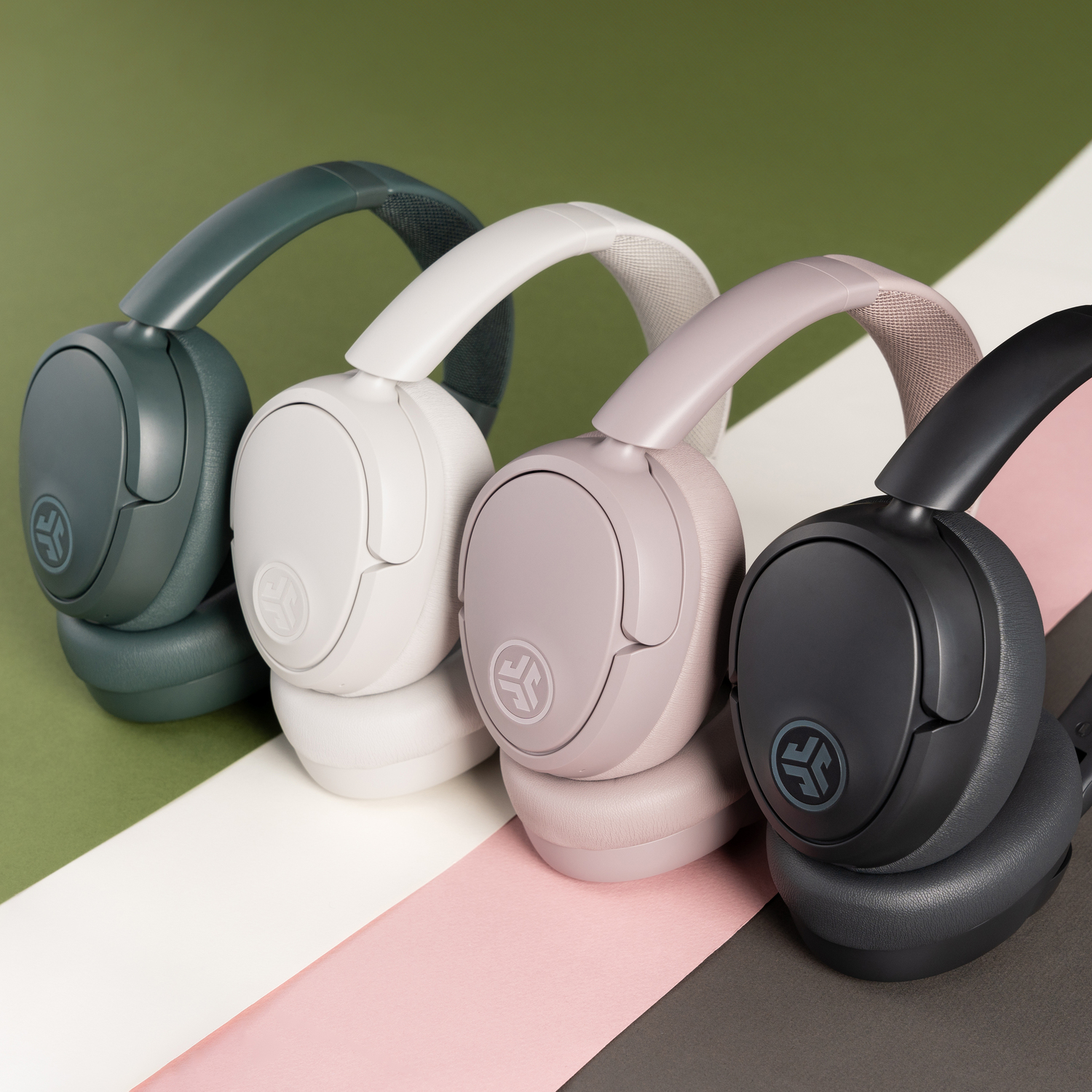 Four pairs of headphones in different colors, lined up on a striped background.