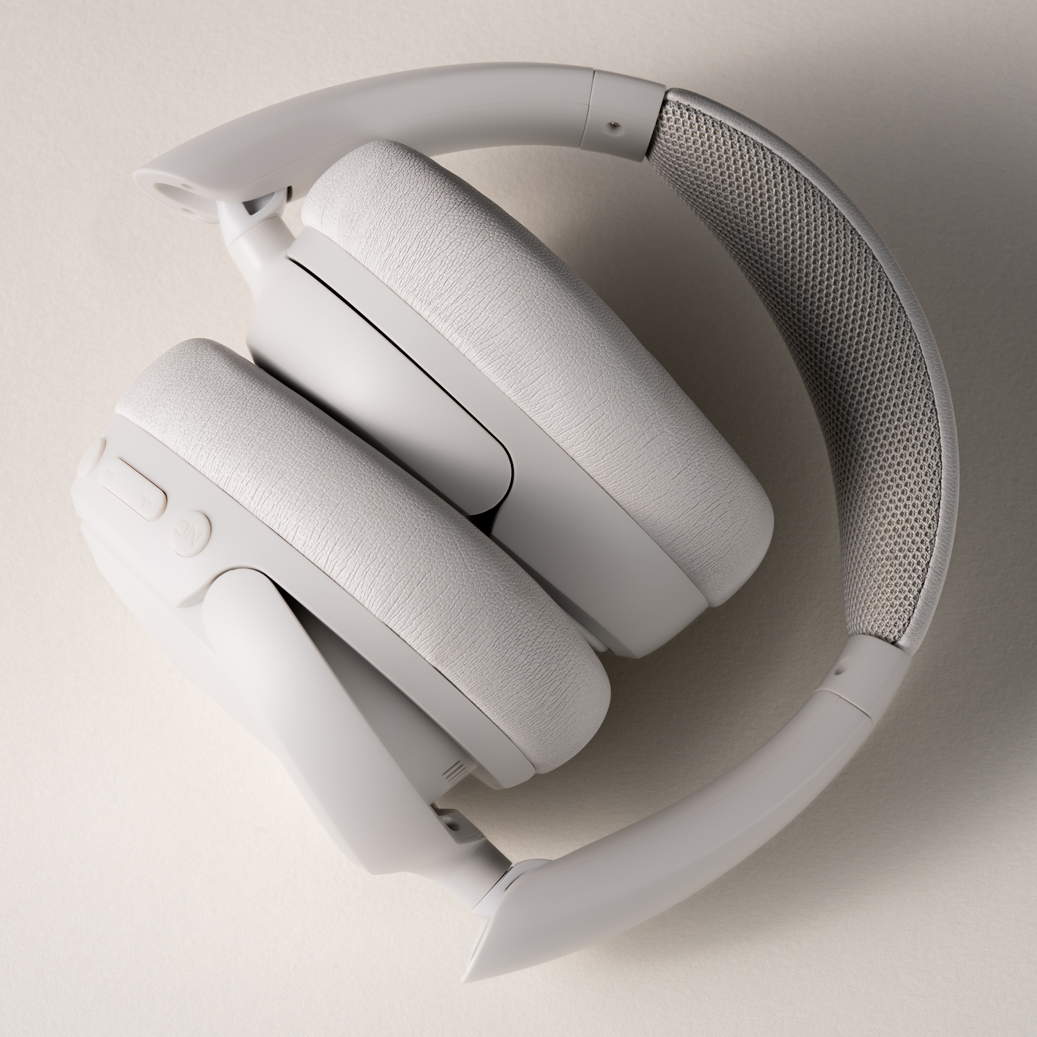 Witte, opgevouwen hoofdtelefoon. De oorschelpen zijn zichtbaar. Grijs mesh-materiaal is ook zichtbaar.