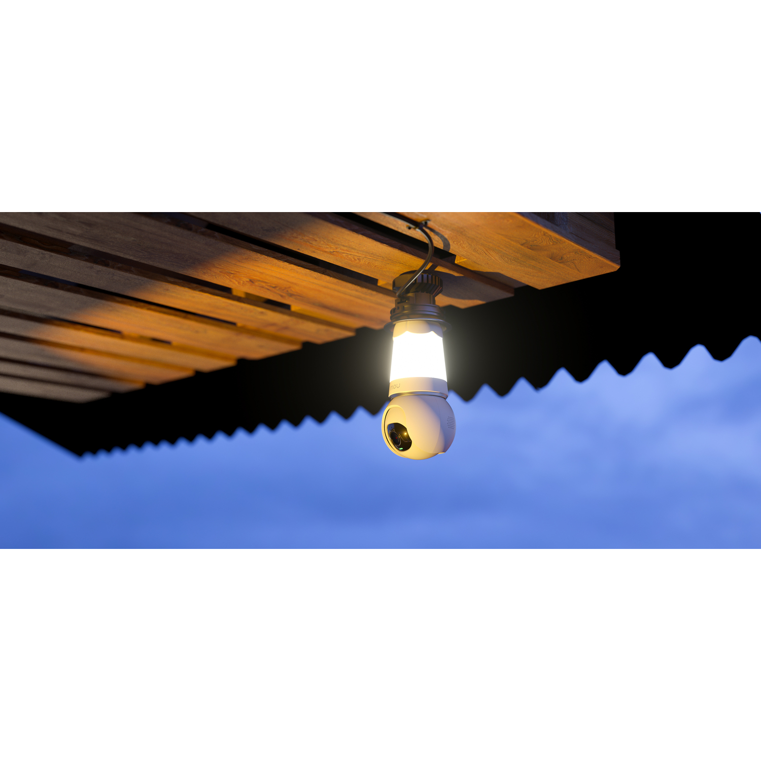 A white, round light with a camera hanging from a wooden structure against a blue sky.
