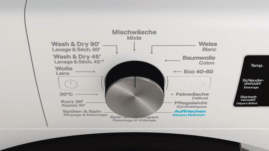 Gros plan du panneau de commande d'une machine à laver avec un cadran et des étiquettes.