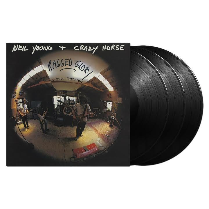 Vinil lemez album borítója zenekarral a színpadon, négy lemez az oldalon.