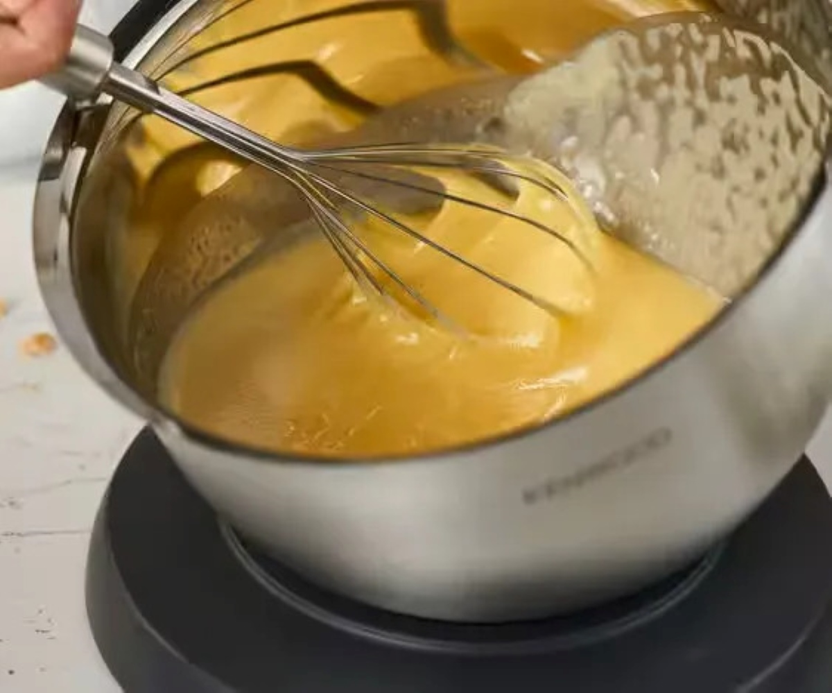 Miska ze stali nierdzewnej przechylona, ubijająca żółty płyn w środku.