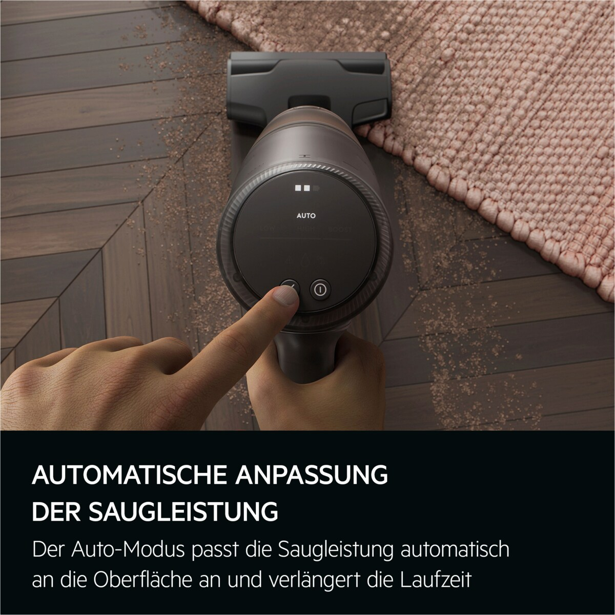Hand drückt Knopf an Staubsauger. Anzeige zeigt 'AUTO'. Der Staubsauger ist auf Holzboden und Teppich.