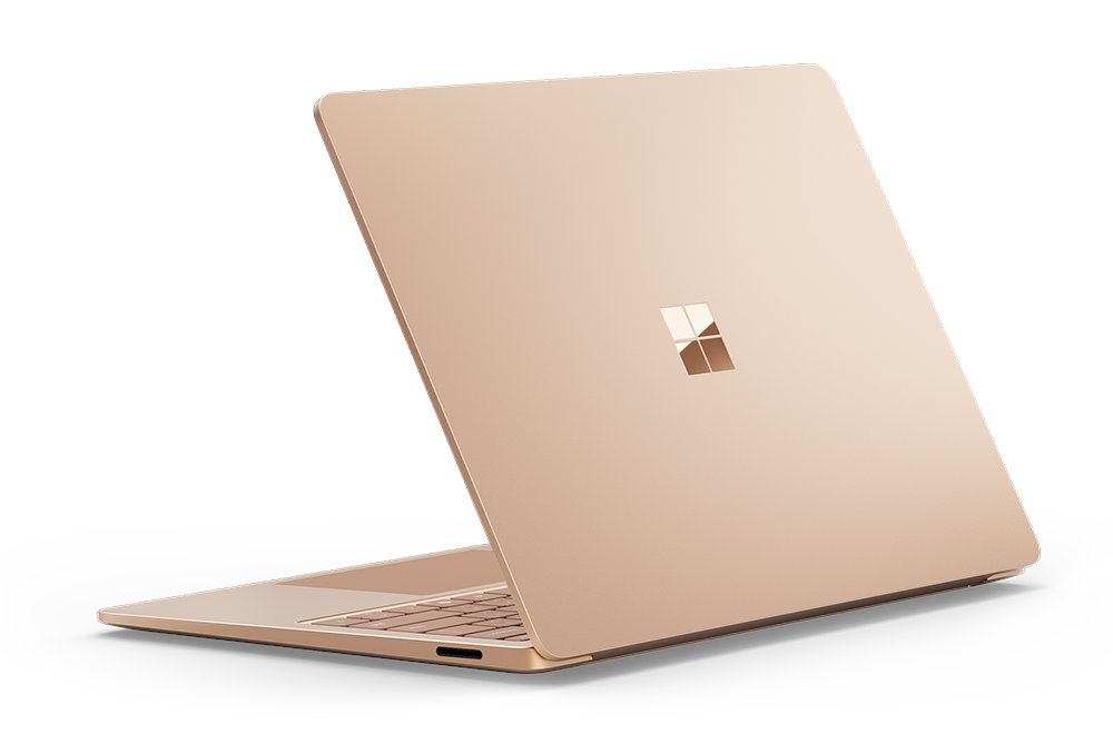 Złoty laptop, zamknięty, widok z tyłu pod kątem. Pokazuje logo Microsoftu.