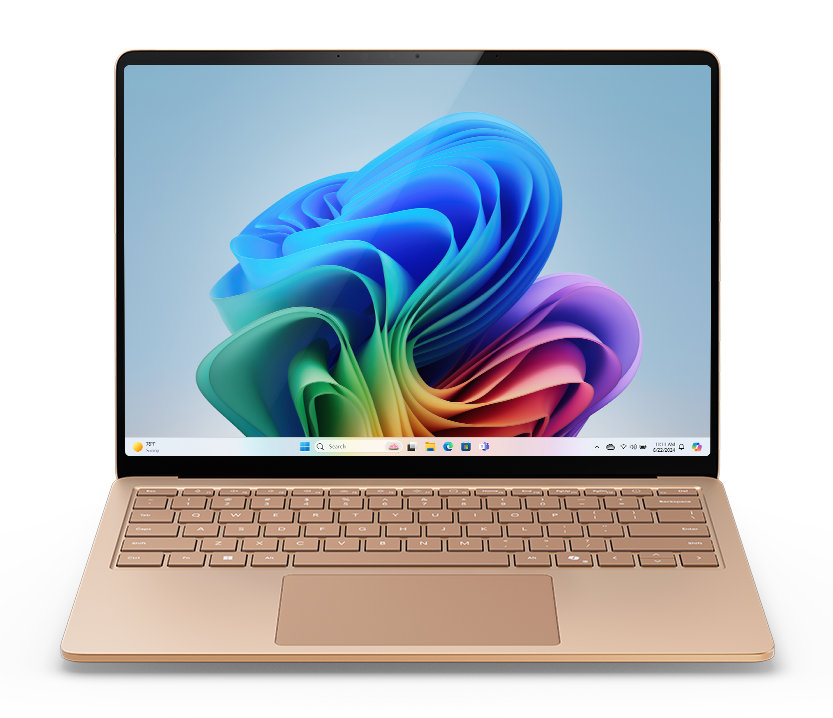 Złoty laptop na białej powierzchni. Ekran wyświetla kolorową, abstrakcyjną tapetę systemu Windows.