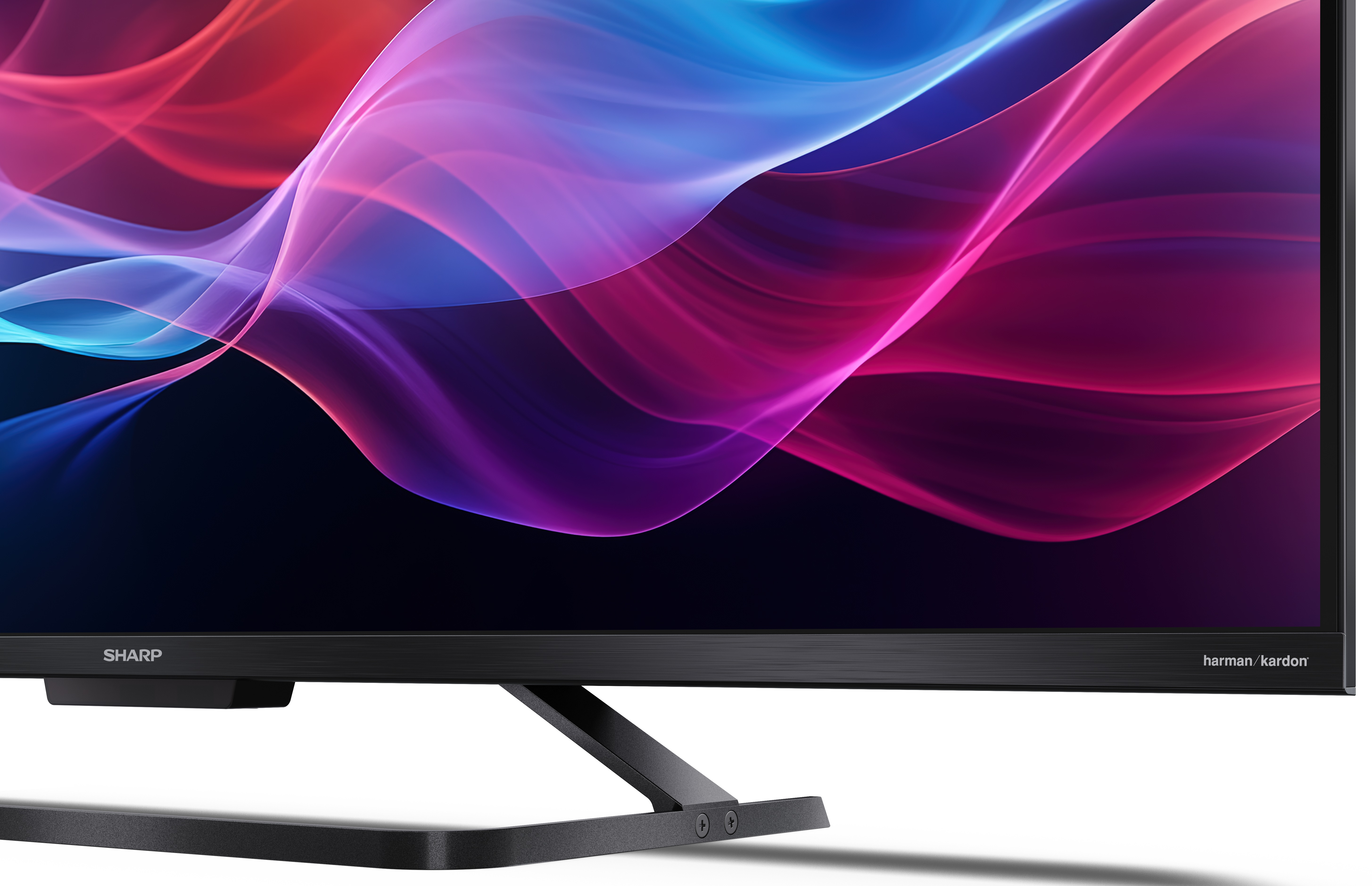 Telewizor z czarną ramką. Wyświetlacz z kolorowymi falami. Logo Harman Kardon po prawej stronie.