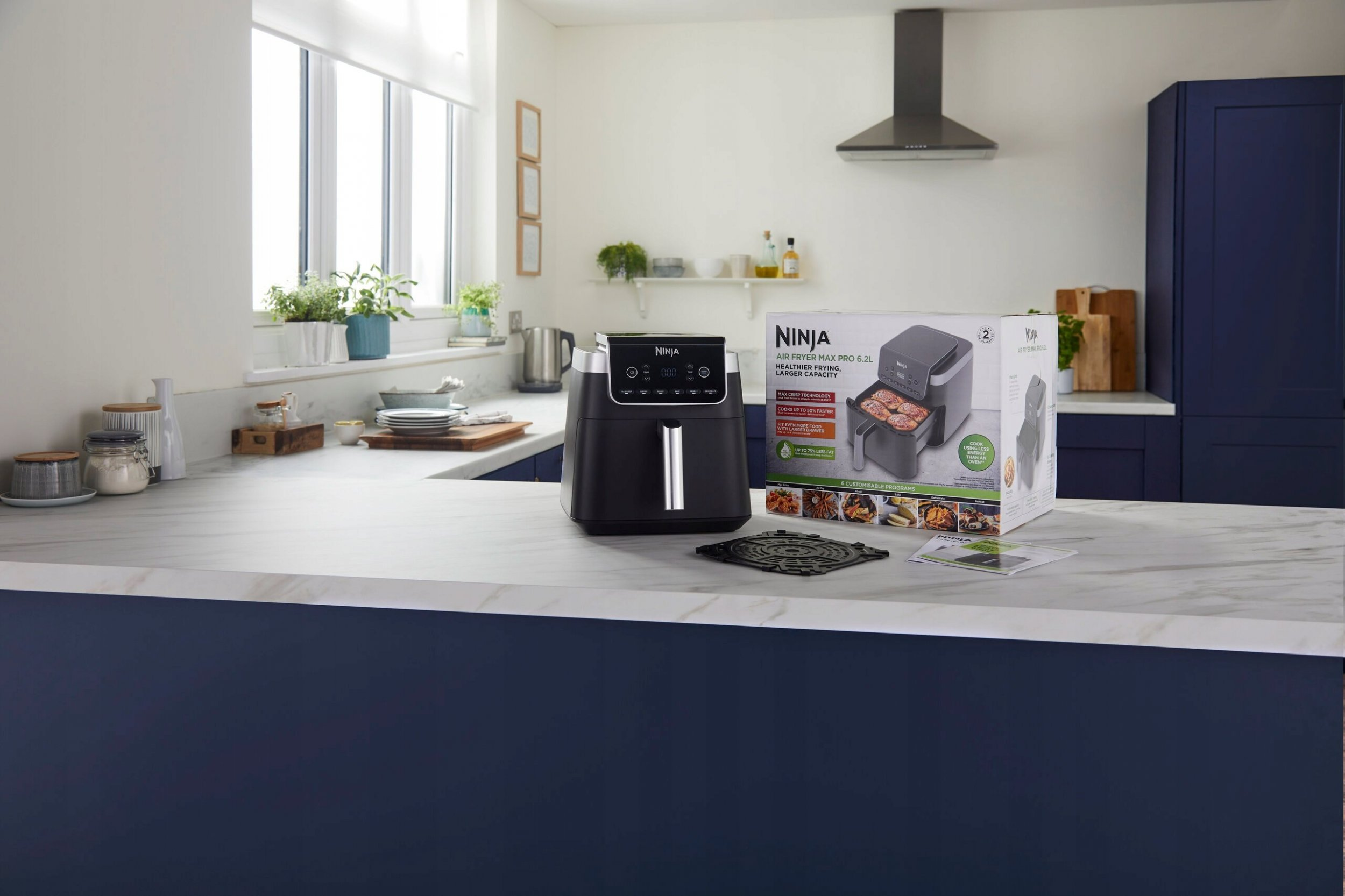 Frytownica powietrzna i pudełko ze zdjęciami jedzenia na blacie kuchennym.