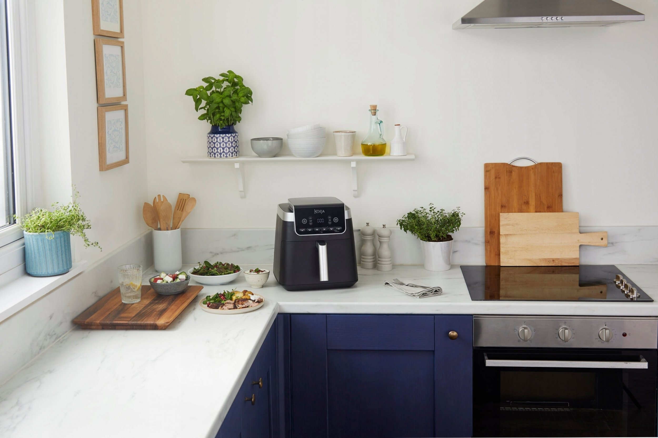 Kuchnia z frytkownicą na blacie. Są też miski z jedzeniem i roślinami.