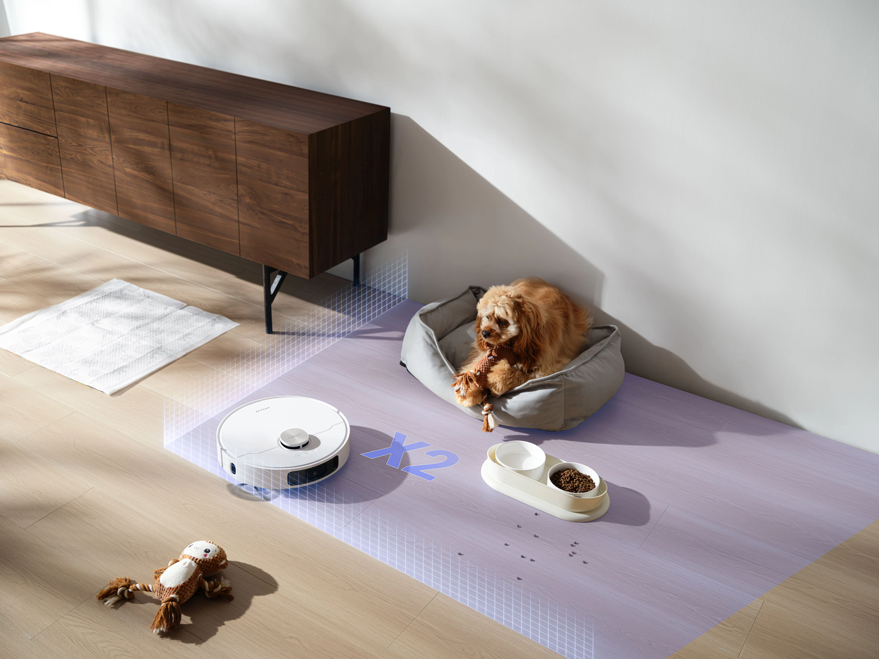 Un cane in un letto, un aspirapolvere robot, ciotole per cibo e acqua su un tappeto.