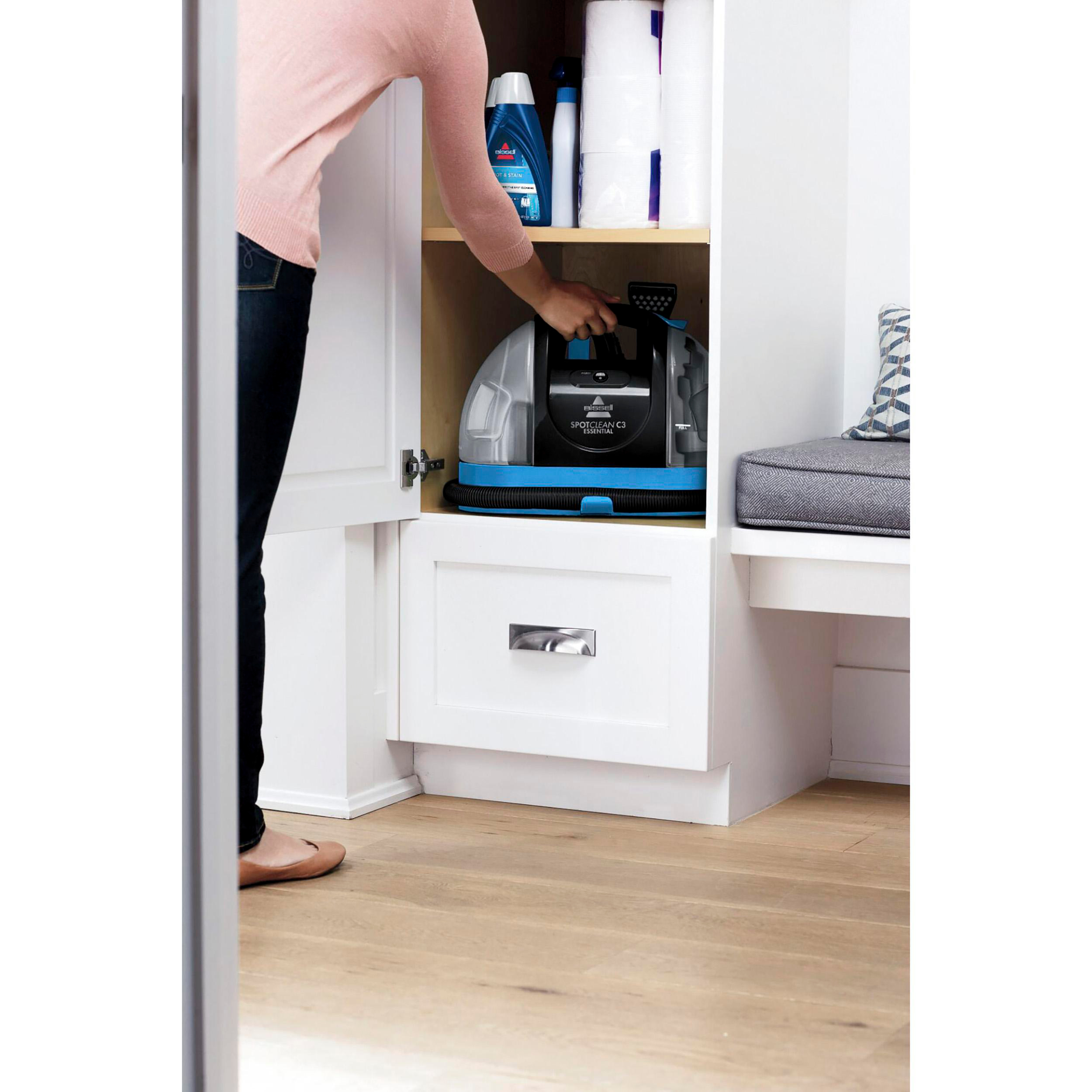 Eine Frau stellt einen Staubsauger in einen Schrank. Blaue und weiße Farben.