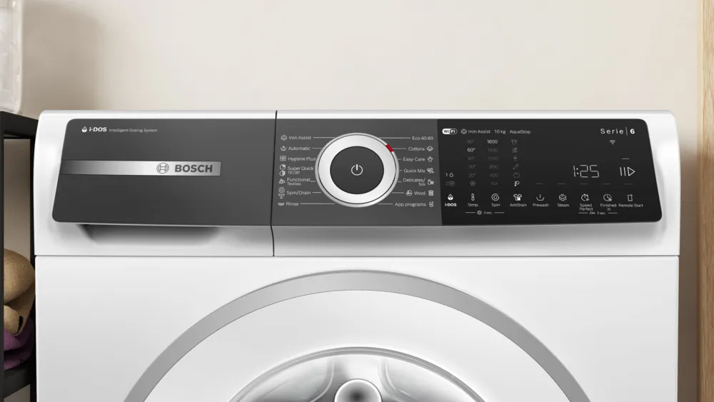 Mosógép elölnézete. Szürke kezelőpanel gombokkal és kijelzővel. Fehér test.