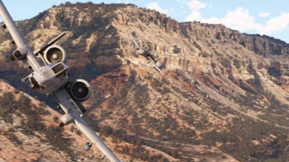 Trois avions de chasse survolant un paysage montagneux aux tons bruns et verts.