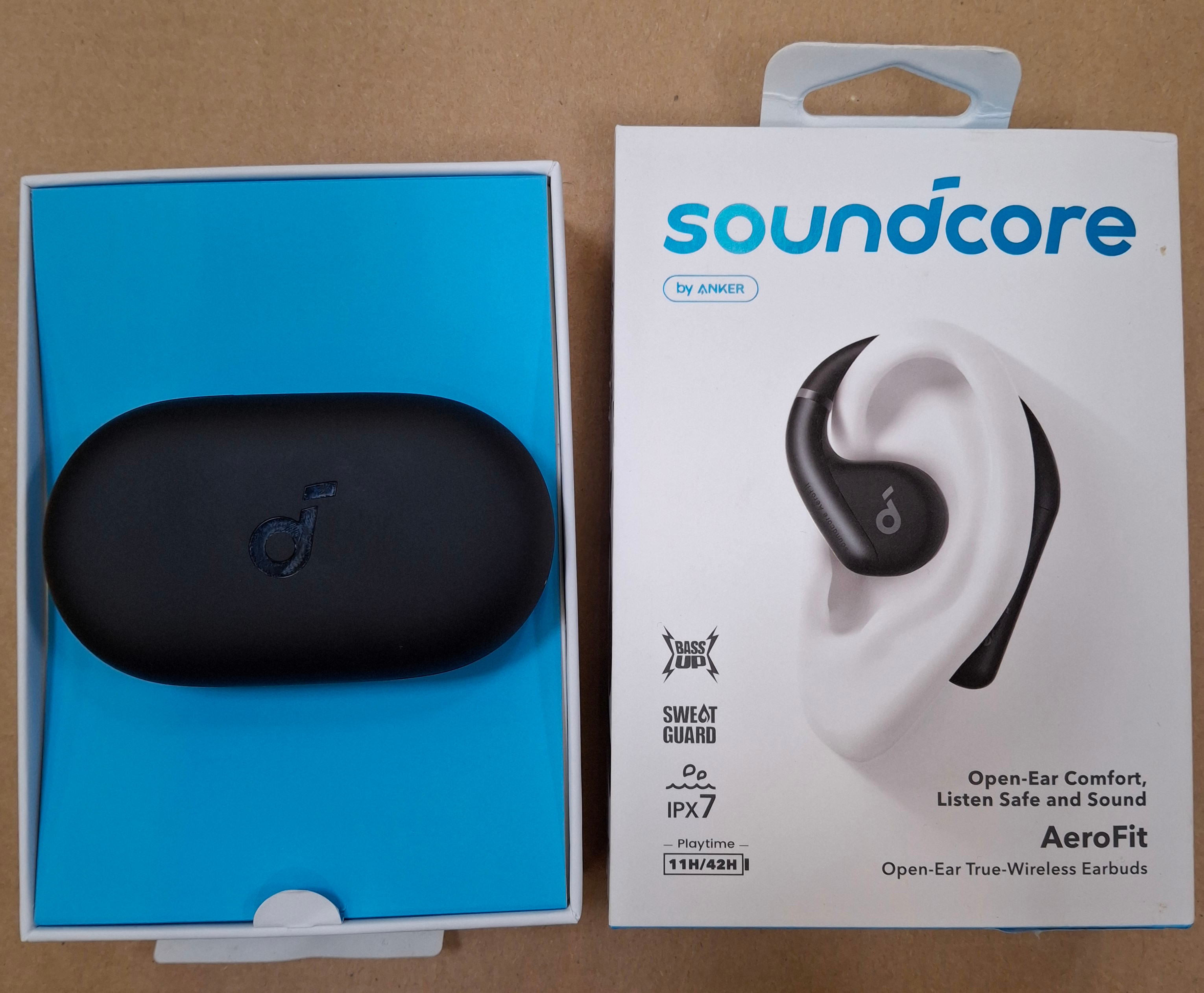Czarne etui na słuchawki i pudełko Soundcore AeroFit. Pudełko pokazuje słuchawki i funkcje, IPX7 oraz 11H/42H czasu odtwarzania.