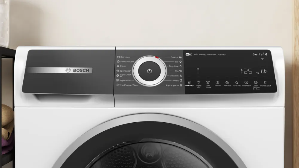 Fehér mosógép vezérlőpanel különböző programválasztási lehetőségekkel és digitális kijelzővel.