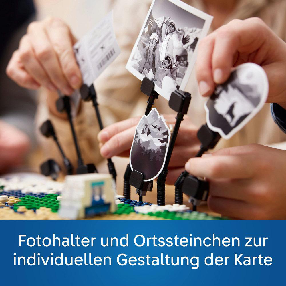 Hände halten Fotos in schwarzen Haltern, mit einer Lego-Szene im Vordergrund. Text unten.