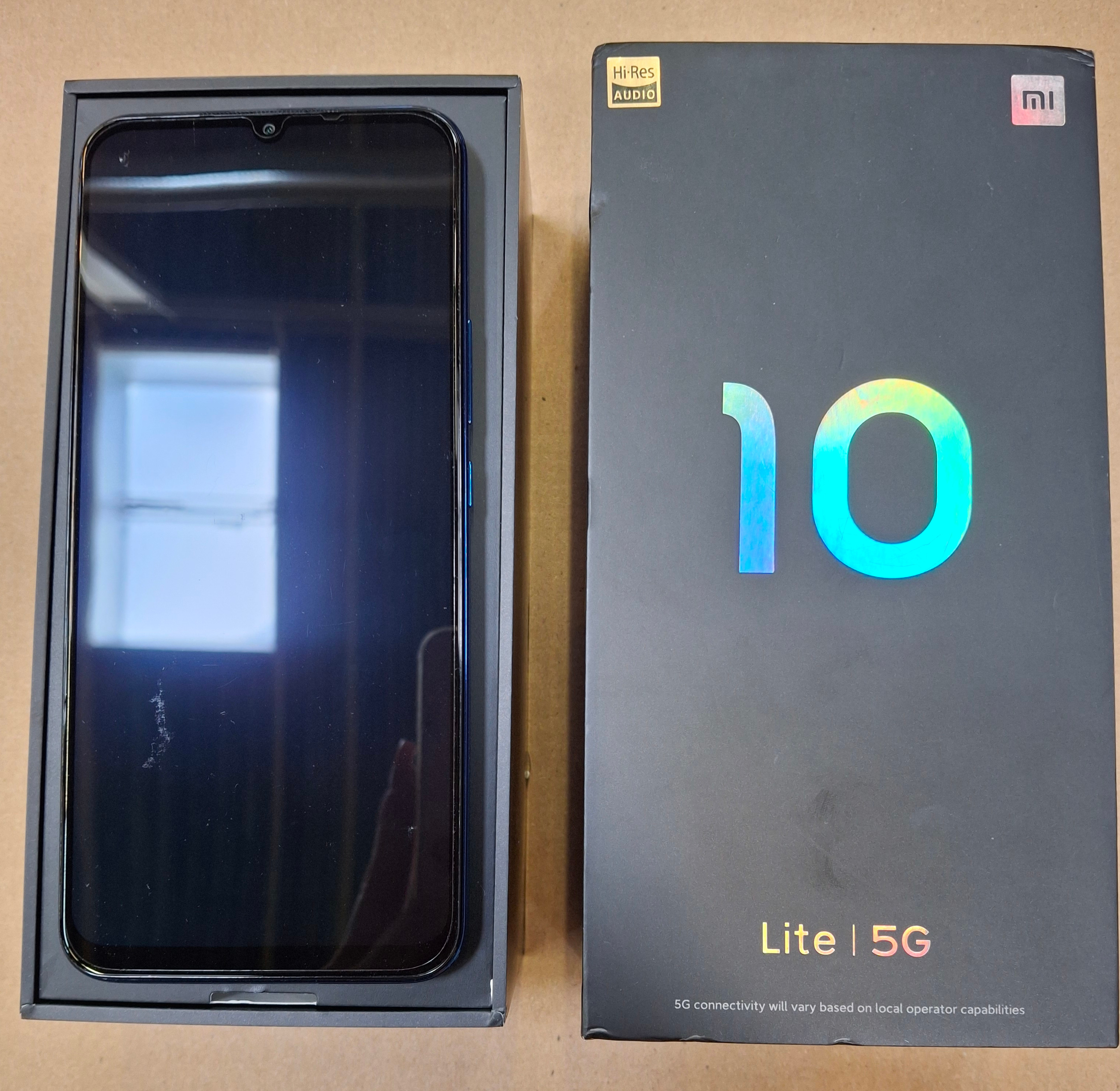 Czarny smartfon w pudełku, wystawiony na stole.