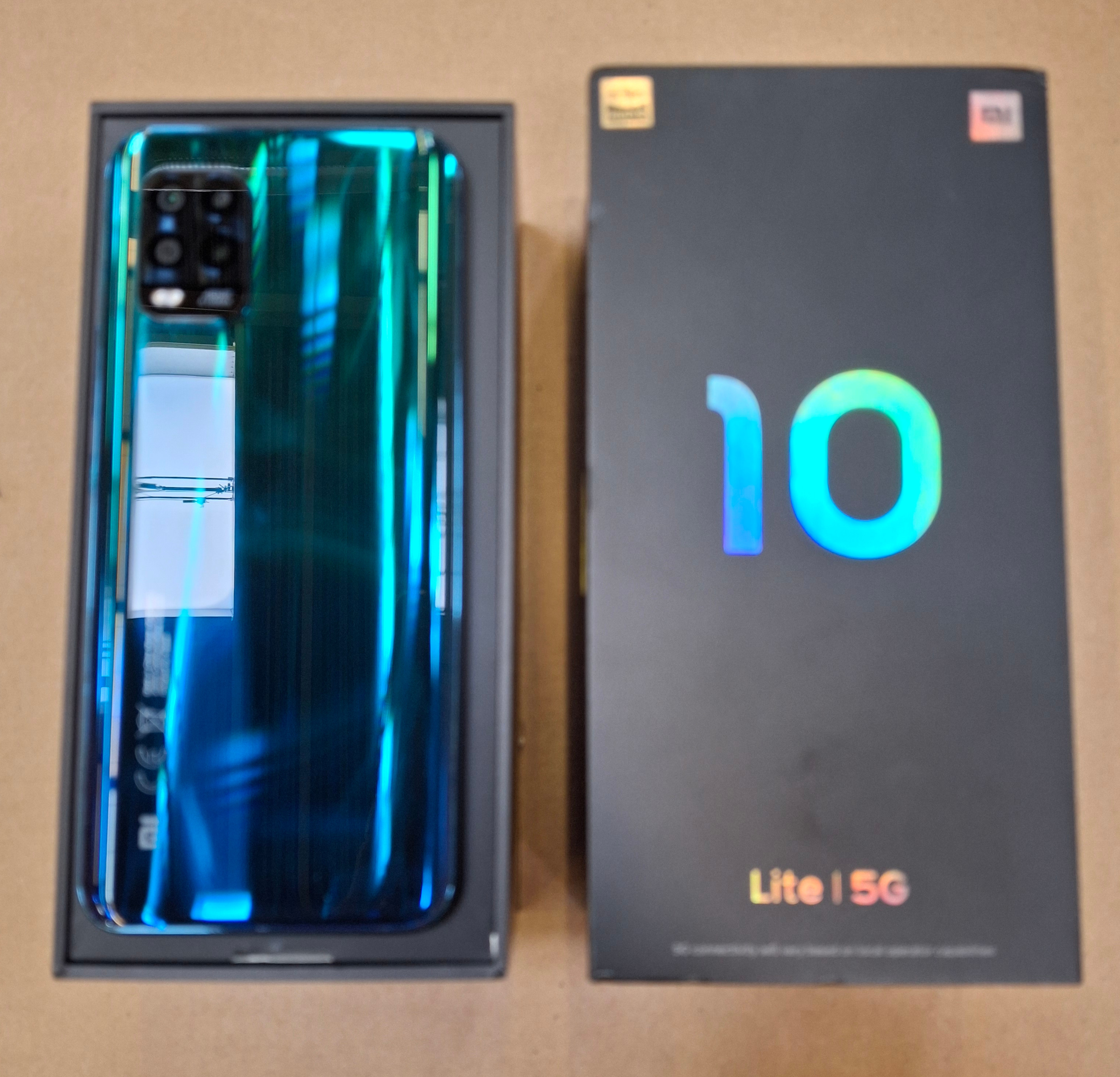 Turkusowy telefon komórkowy w czarnym pudełku obok czarnego pudełka z numerem 10 w kolorze niebieskim.