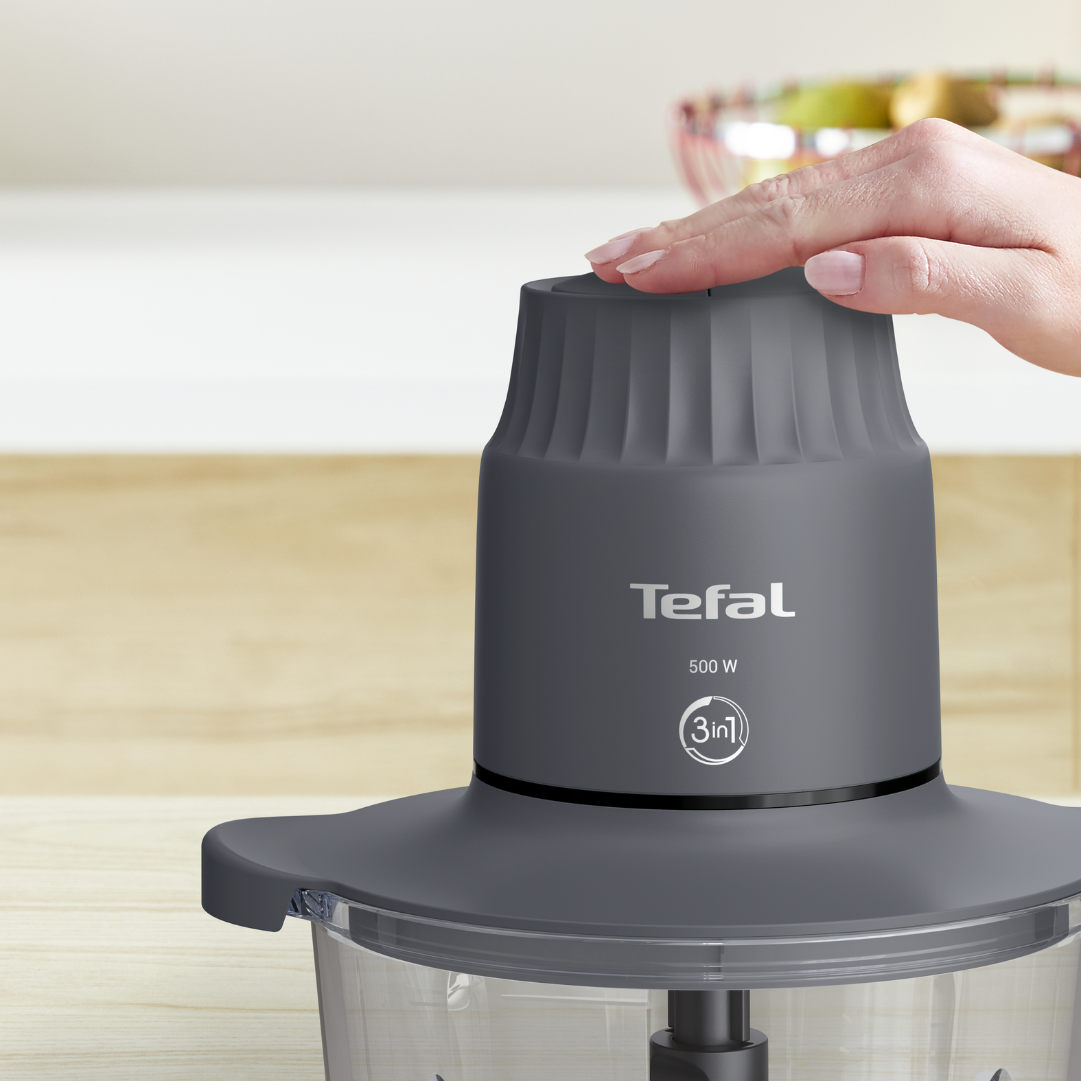 Egy kéz megérinti a szürke Tefal aprítót. Közelkép az eszközről.