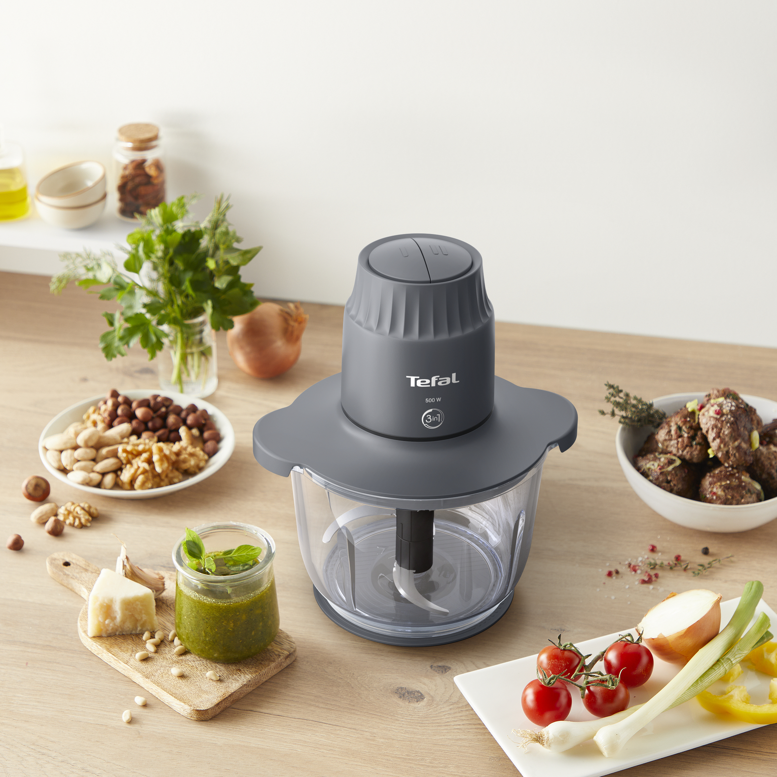 Tefal konyhai robotgép fa felületen, olyan hozzávalókkal körülvéve, mint a dió és a pesto.