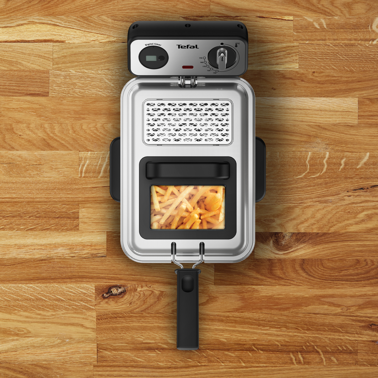 Felülnézet egy fritőzről, benne egy kosár sült krumplival. A márka a Tefal.