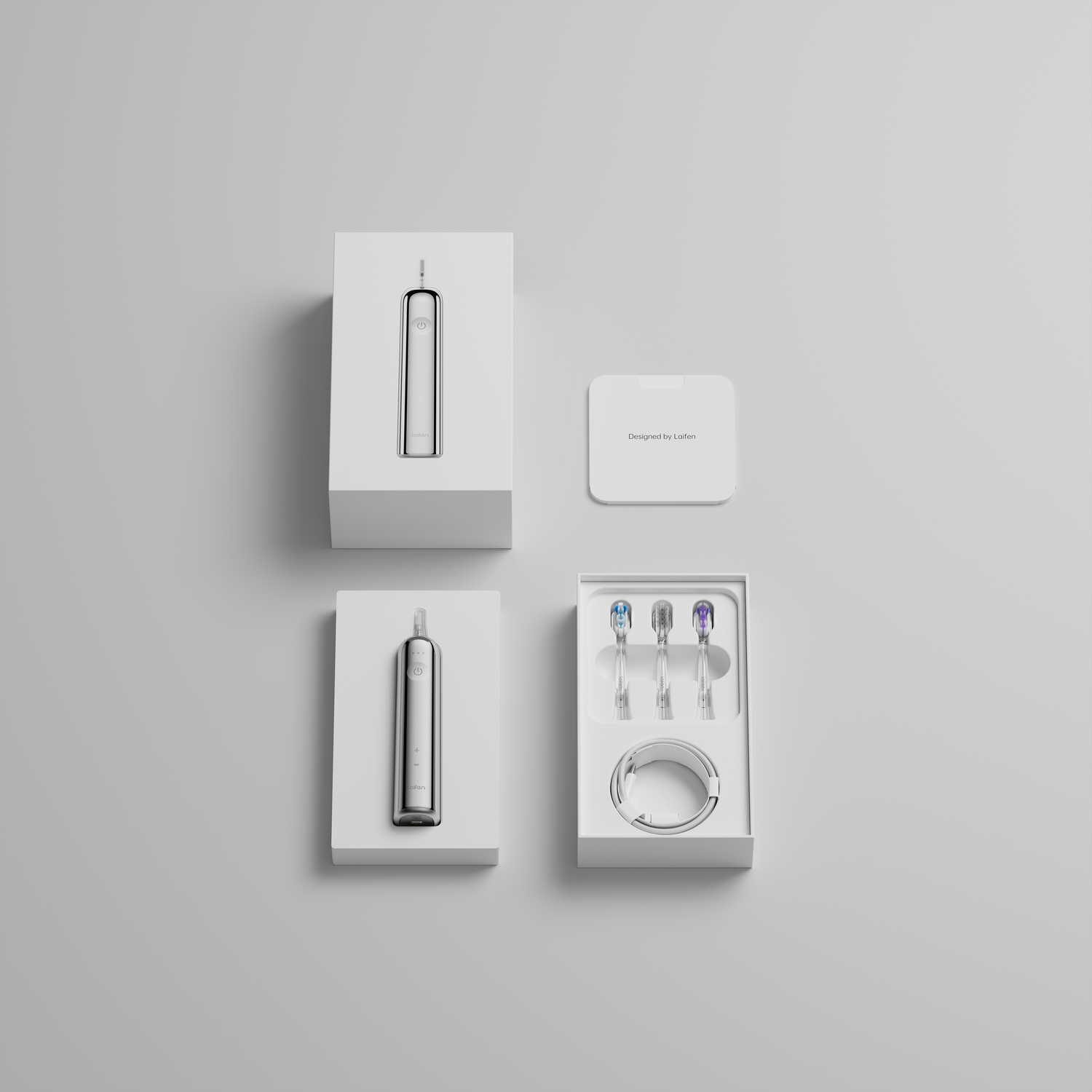 Witte elektrische tandenborstelset in dozen, met borstelkoppen en oplader, op een lichtgrijze ondergrond.
