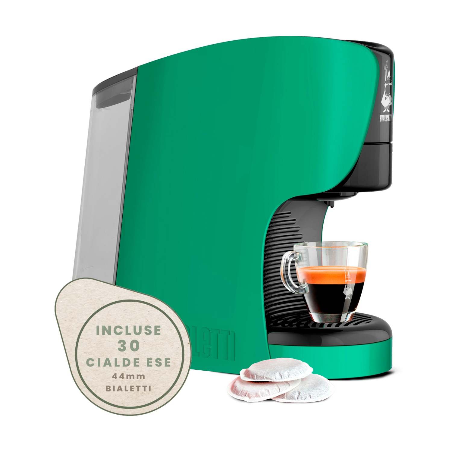 Macchina da caffè verde con tazza in vetro, caffè e cialde su superficie bianca.