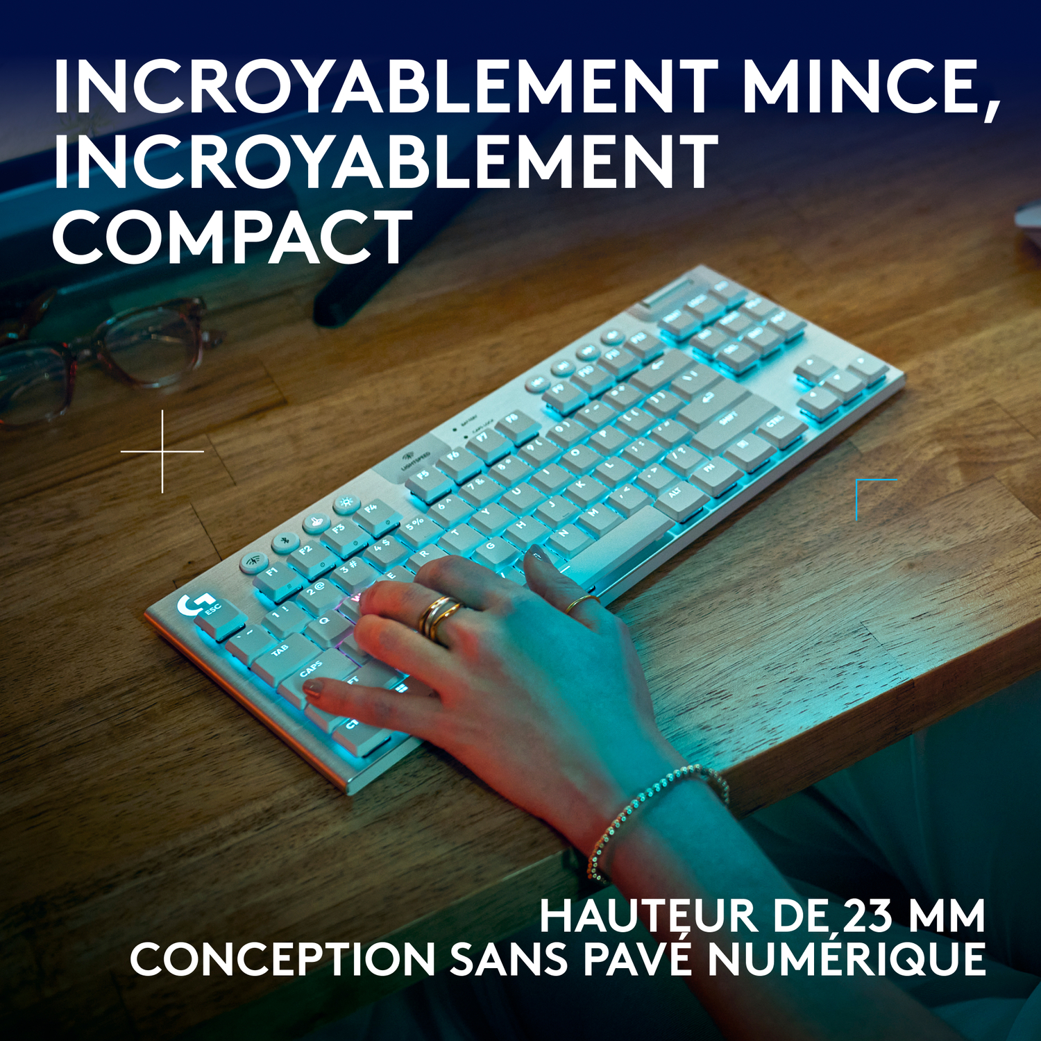 Personne utilisant un clavier avec des lumières. Texte : Hauteur 23 mm, design sans pavé numérique.
