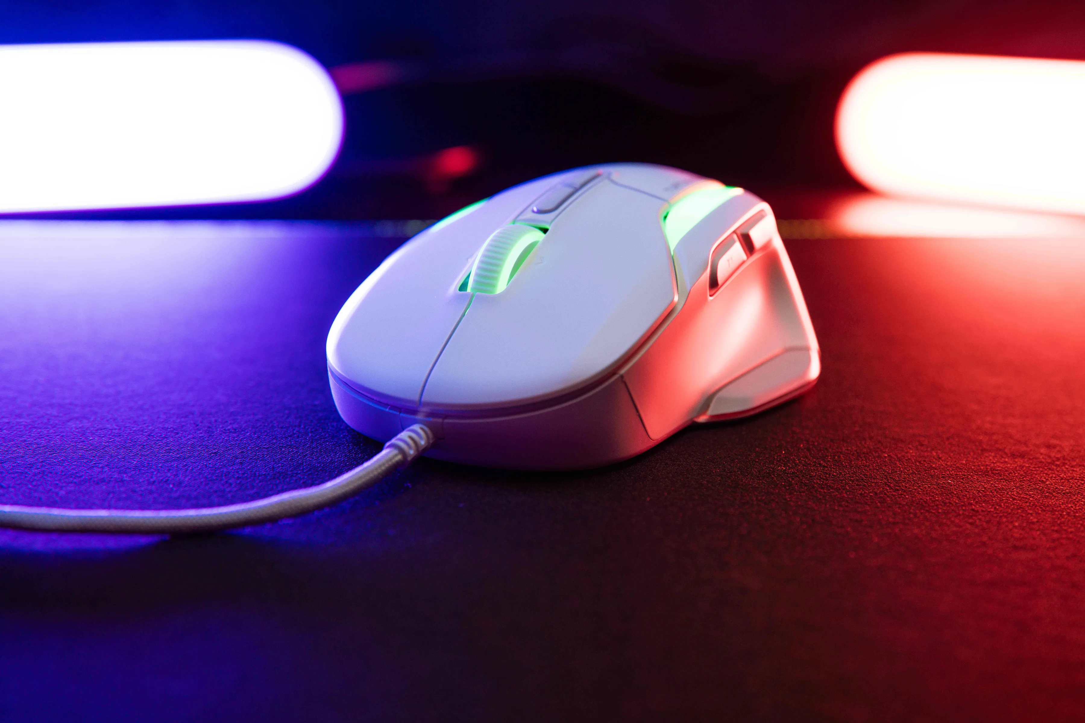 Un mouse da gioco bianco su una superficie nera con luce rossa e blu sullo sfondo.
