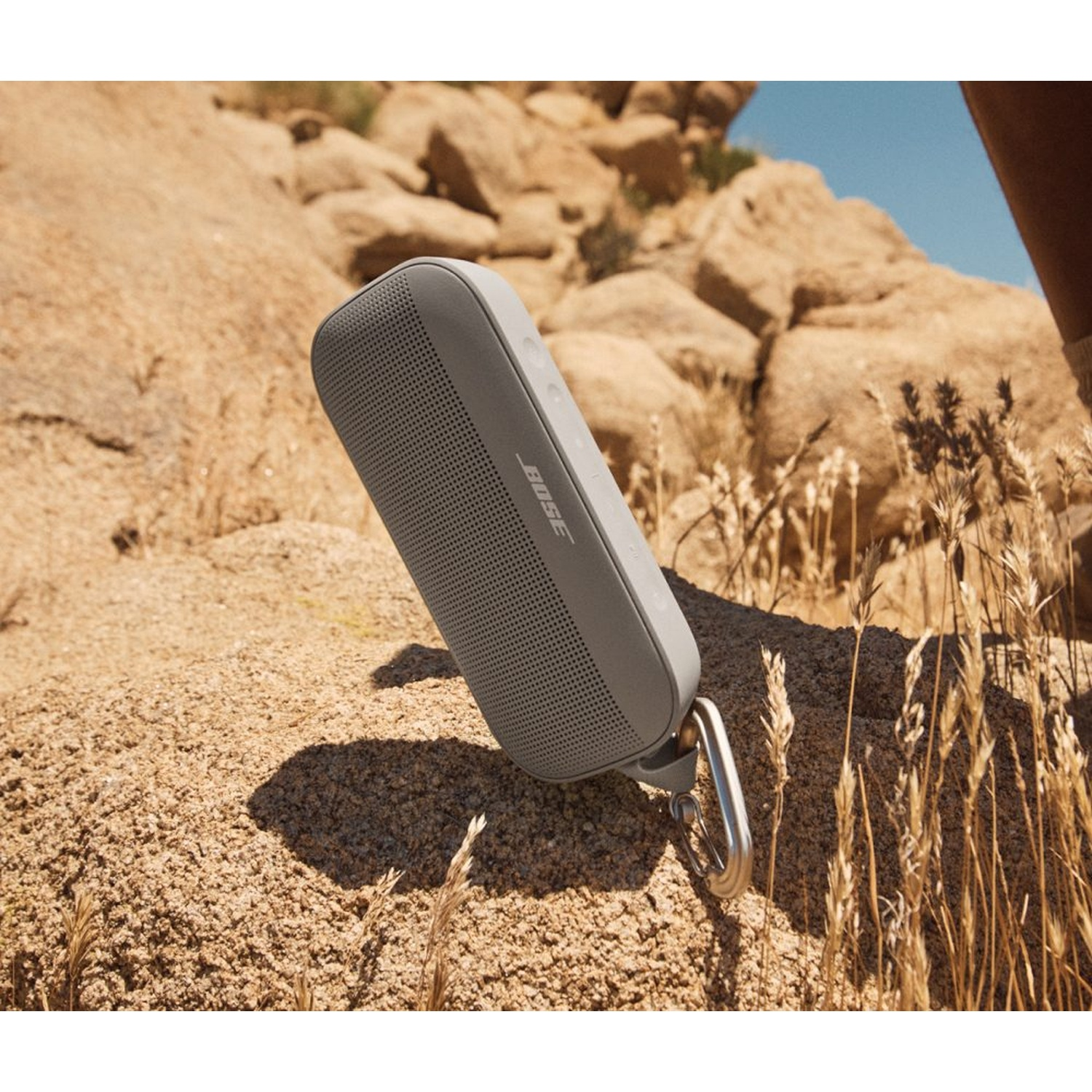 Altoparlante portatile Bose grigio attaccato a una roccia con un moschettone.
