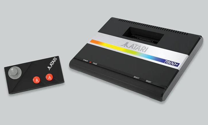 Consola de juegos Atari 7800+ con joystick y mando. La consola es negra y gris.
