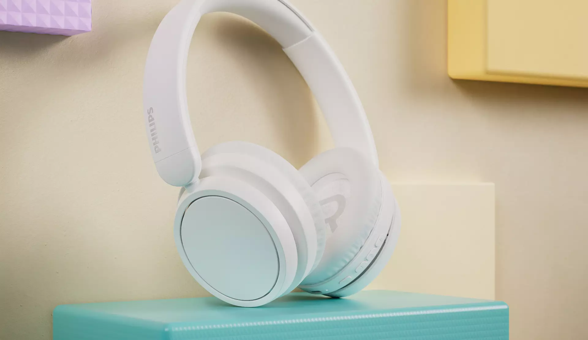 Mavi bir bloğun üzerinde beyaz bir Philips kulaklık, arka planda diğer renkler.
