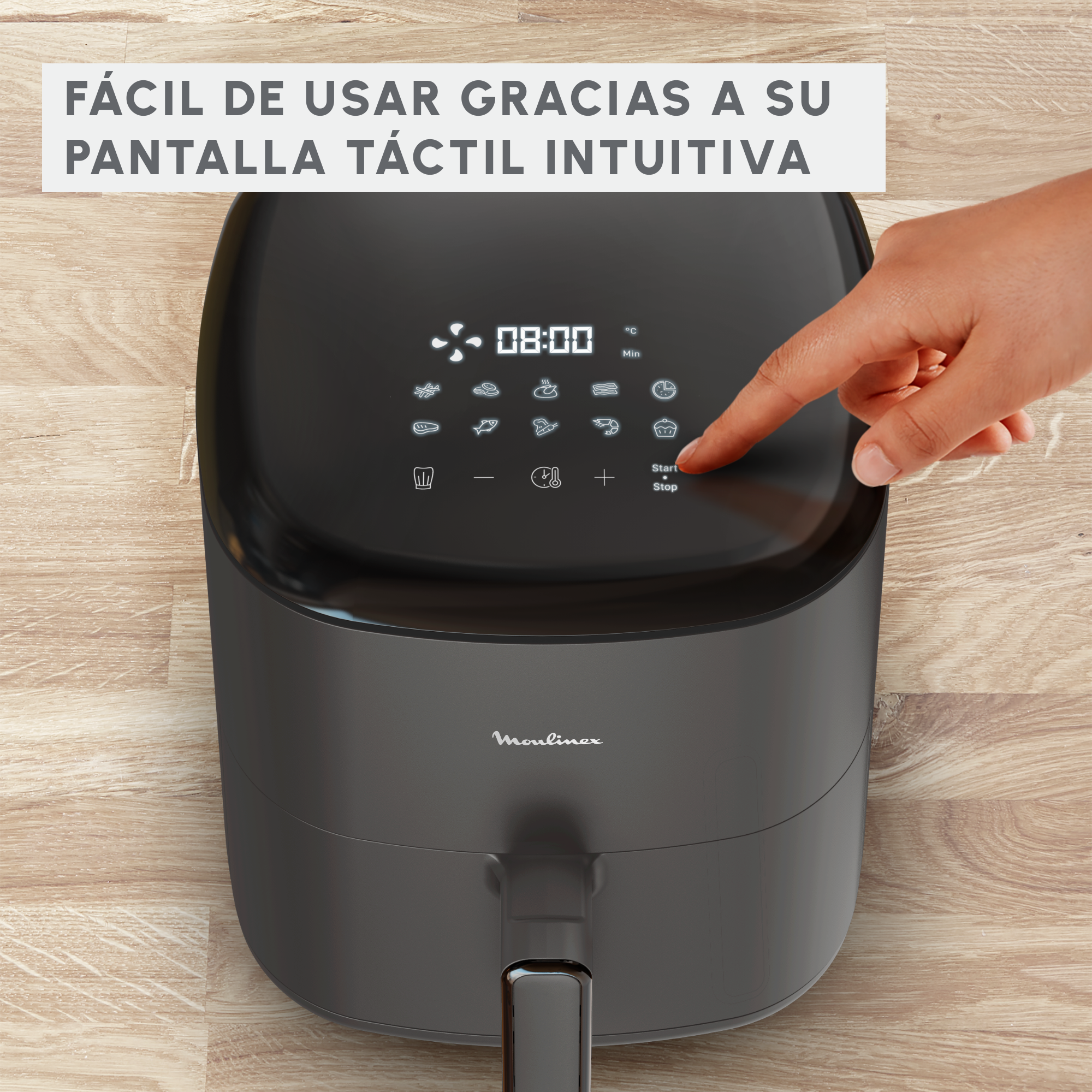 Freidora de aire Moulinex negra, mano del usuario señalando la pantalla táctil, fondo de madera.