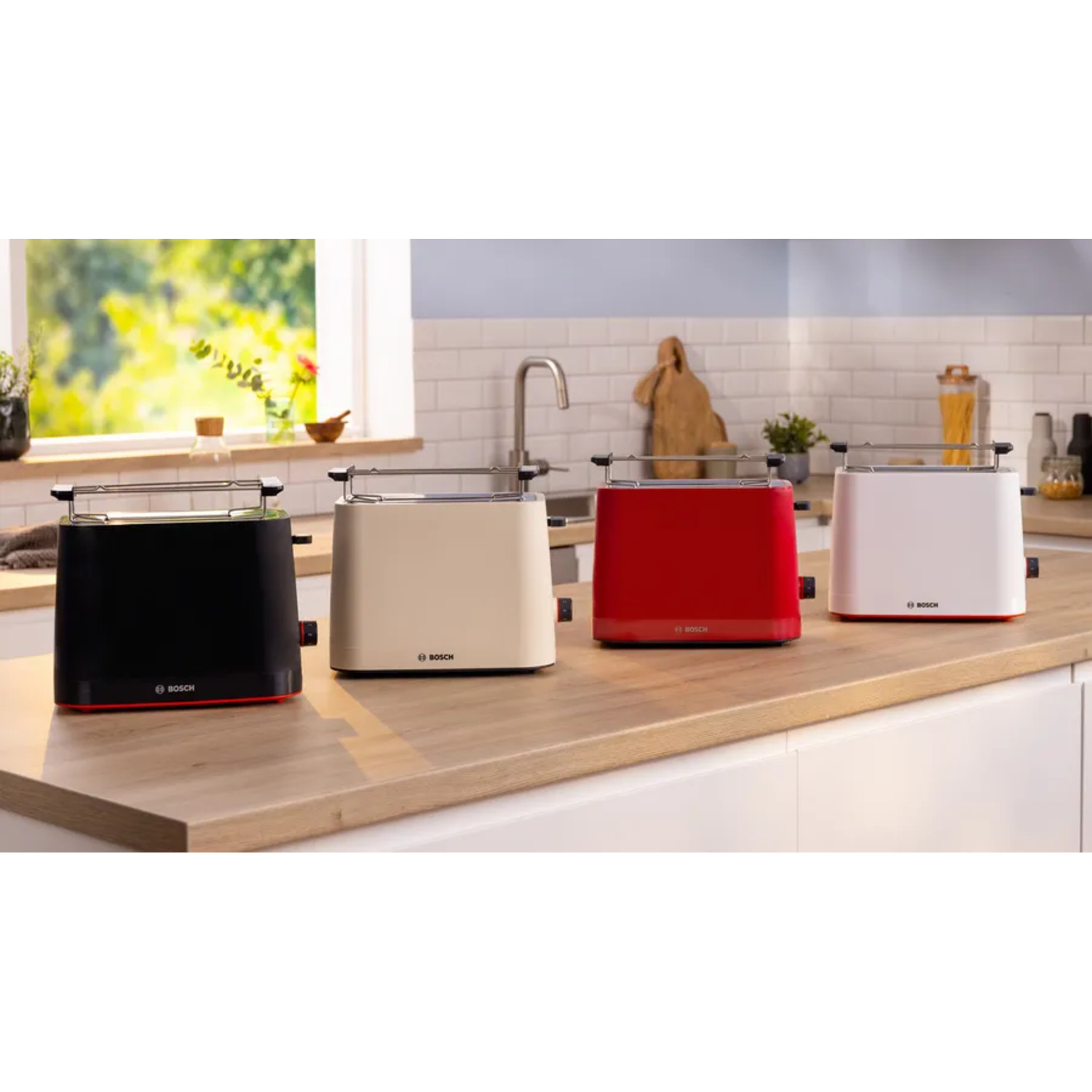 Four toasters of different colors, black, beige, red, and white, on a kitchen counter.