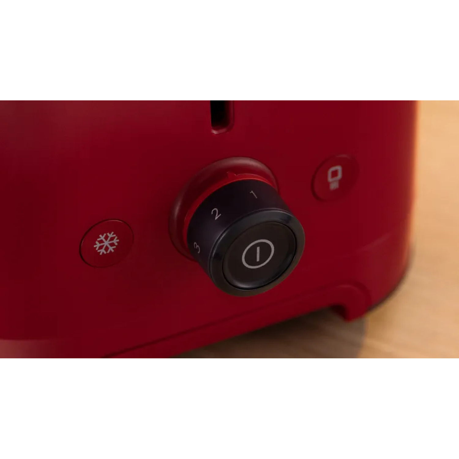 Toaster detail, red body, black dial with numbers and power symbol, and snowflake button.