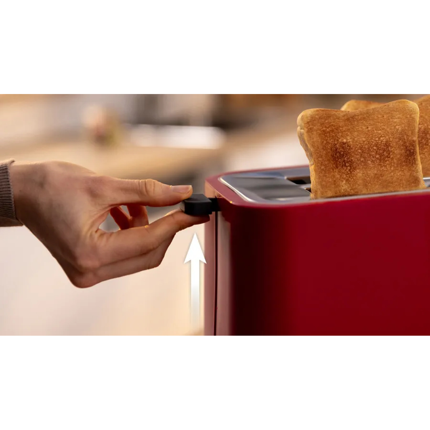 A person's hand operating a red toaster. Toasts are inside.