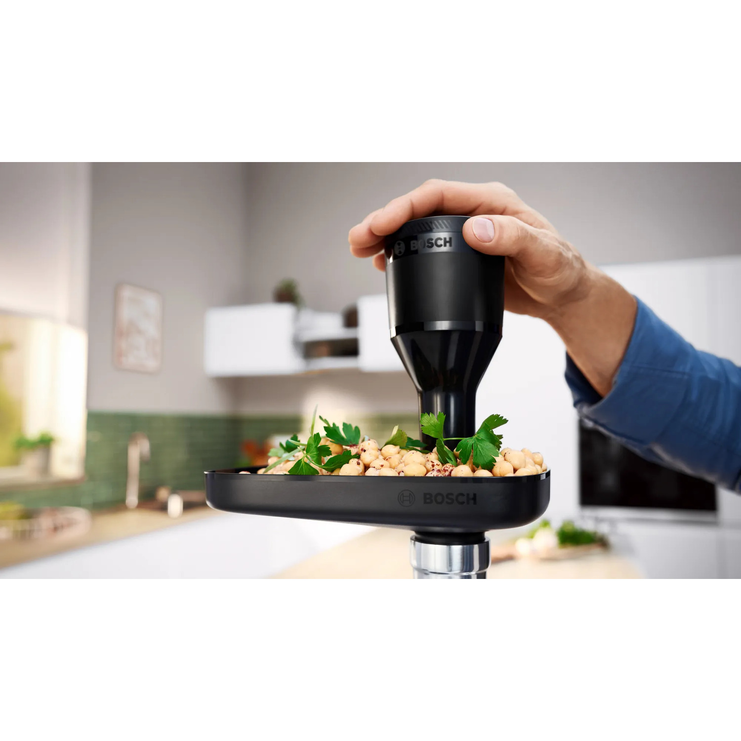Une personne utilisant un robot culinaire avec des herbes et de la nourriture.