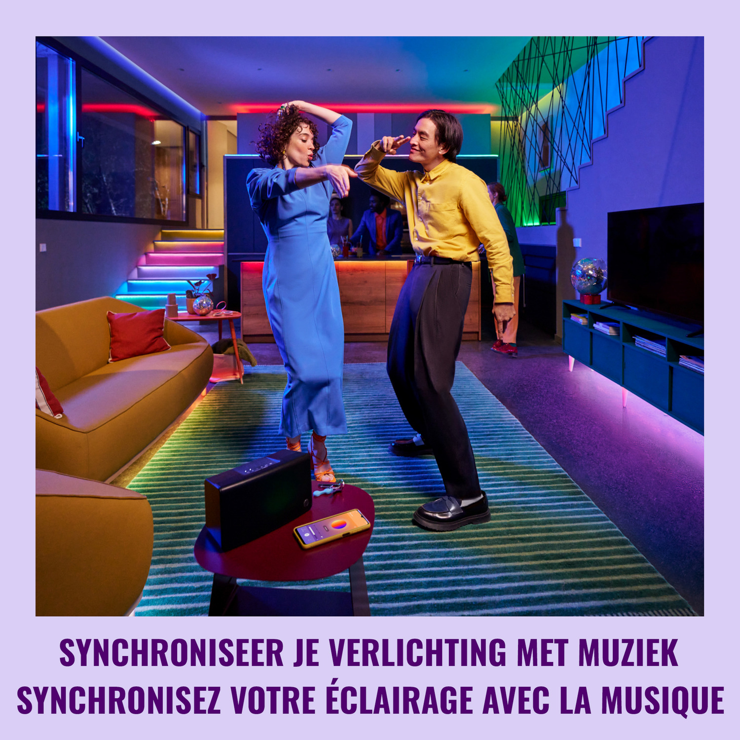 Deux personnes dansant dans une pièce avec des lumières colorées et une enceinte.