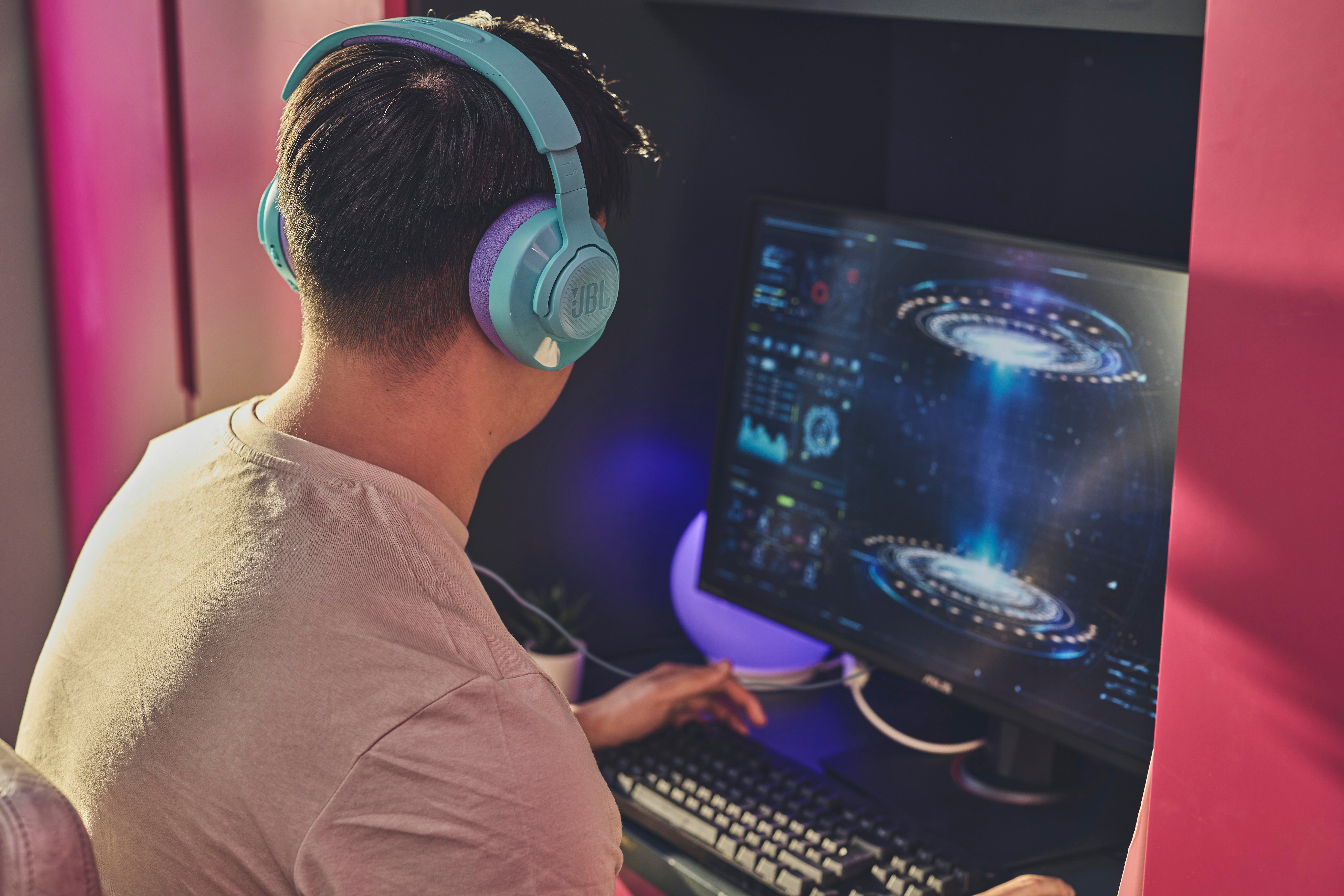 Person mit blau-violetten Kopfhörern beim Spielen.