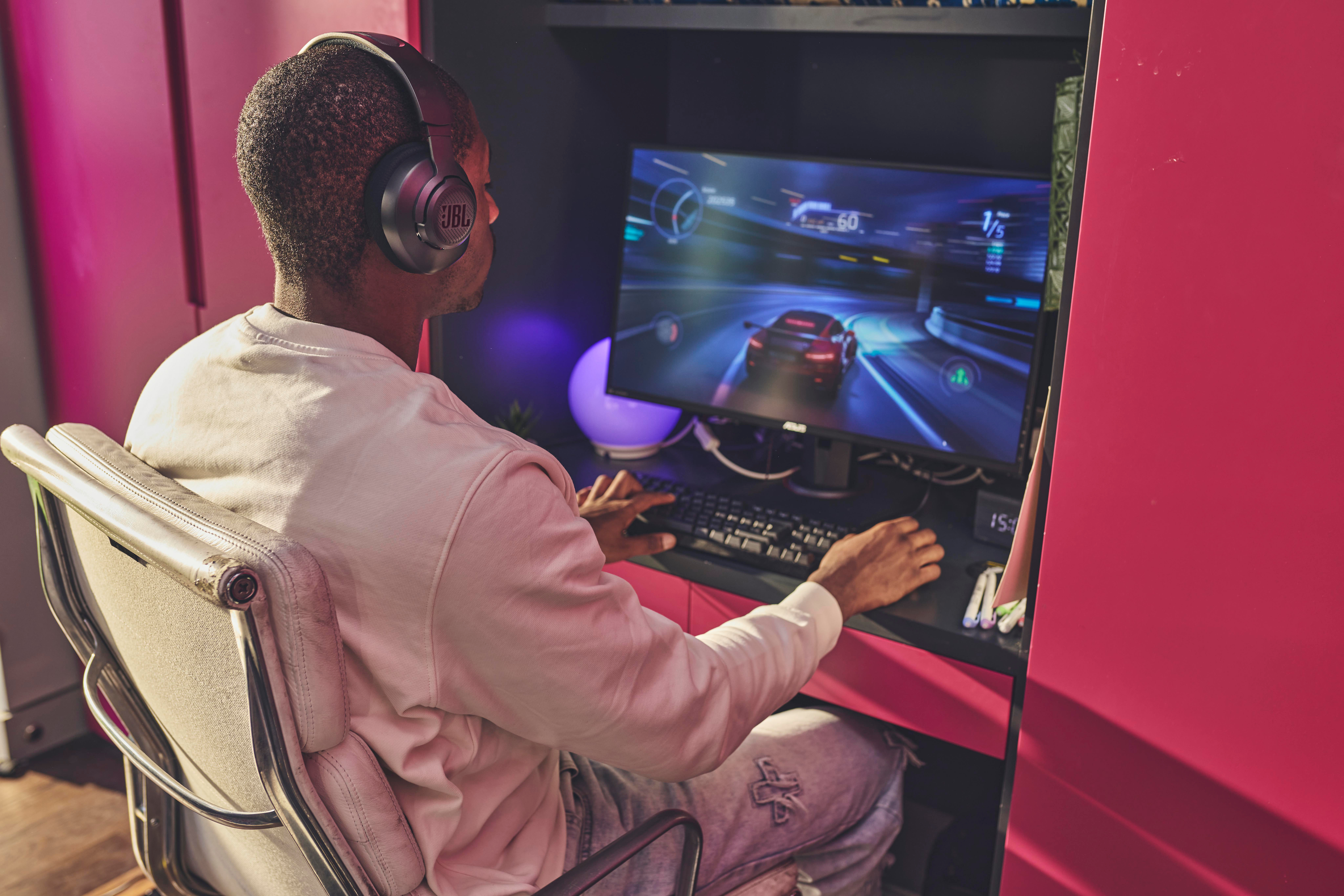 Mann mit Kopfhörern, der auf einem Computer mit einem Rennspiel spielt.