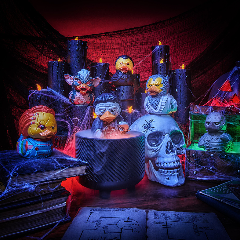 Halloween jelenet horror karakternek öltözött gumikacsákkal, gyertyákkal és egy koponyával.
