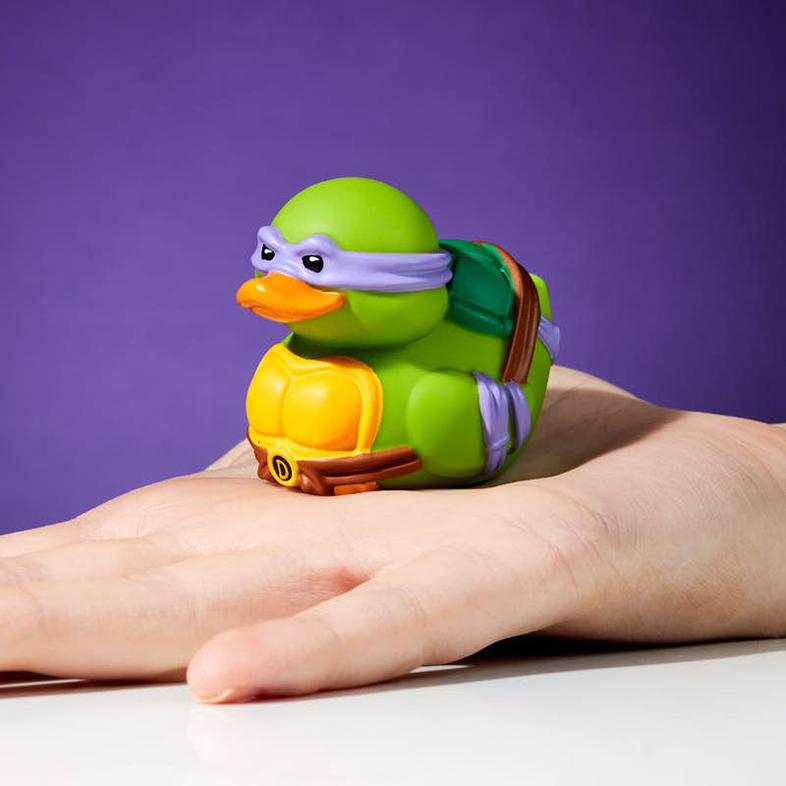 Zöld gumi kacsa, TMNT Donatello, kézben. Lila háttér.