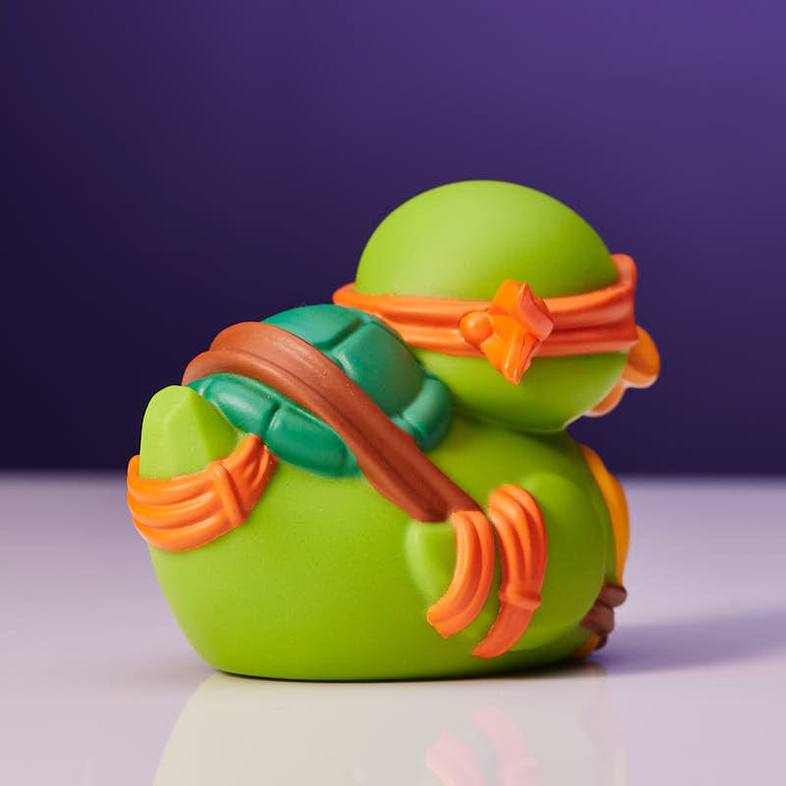 Egy gumikacsa, mely egy Teenage Mutant Ninja Turtle-nek van öltözve, lila háttérrel.