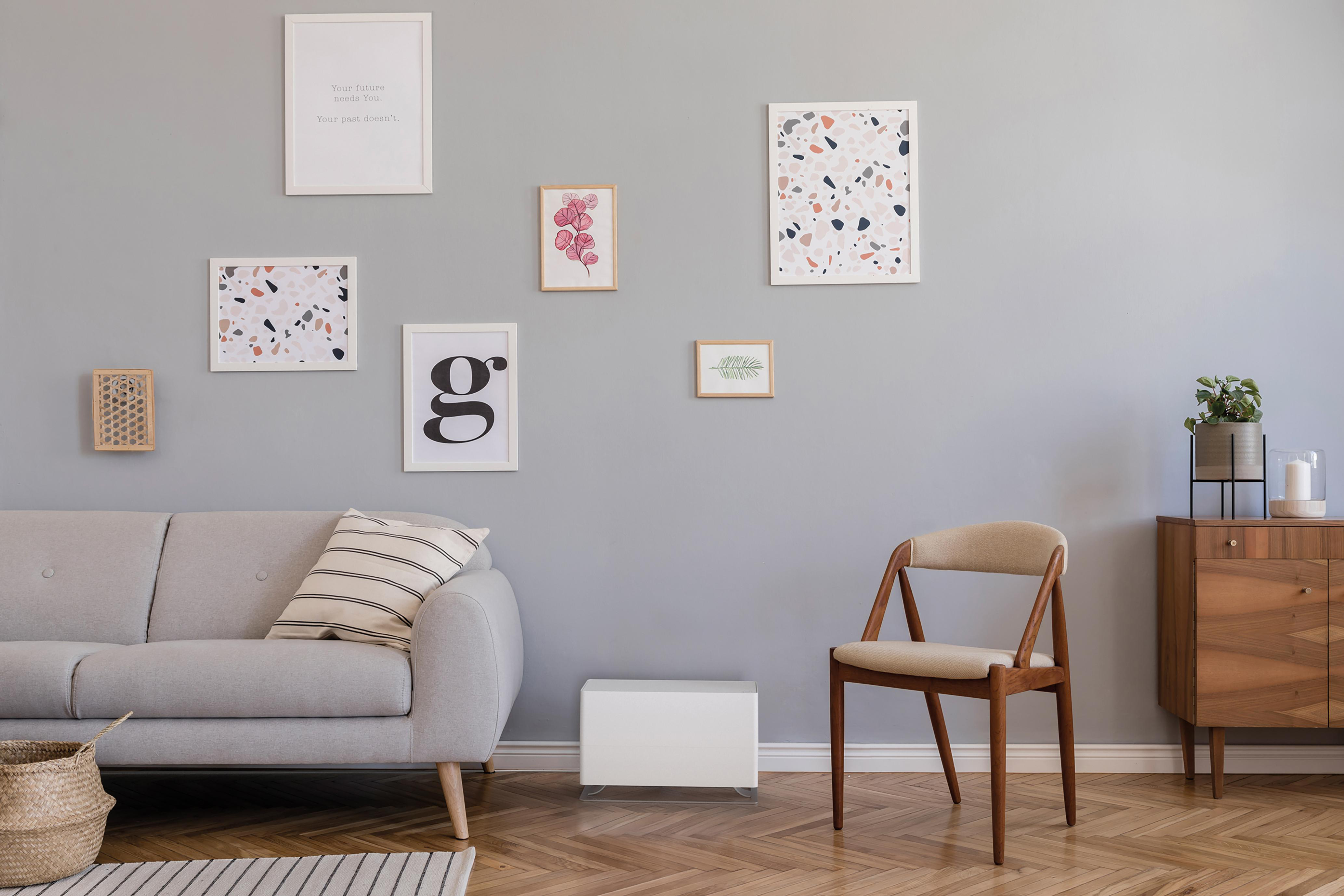 Ein Wohnzimmer mit gerahmten Bildern an einer grauen Wand und einem Holzschrank.