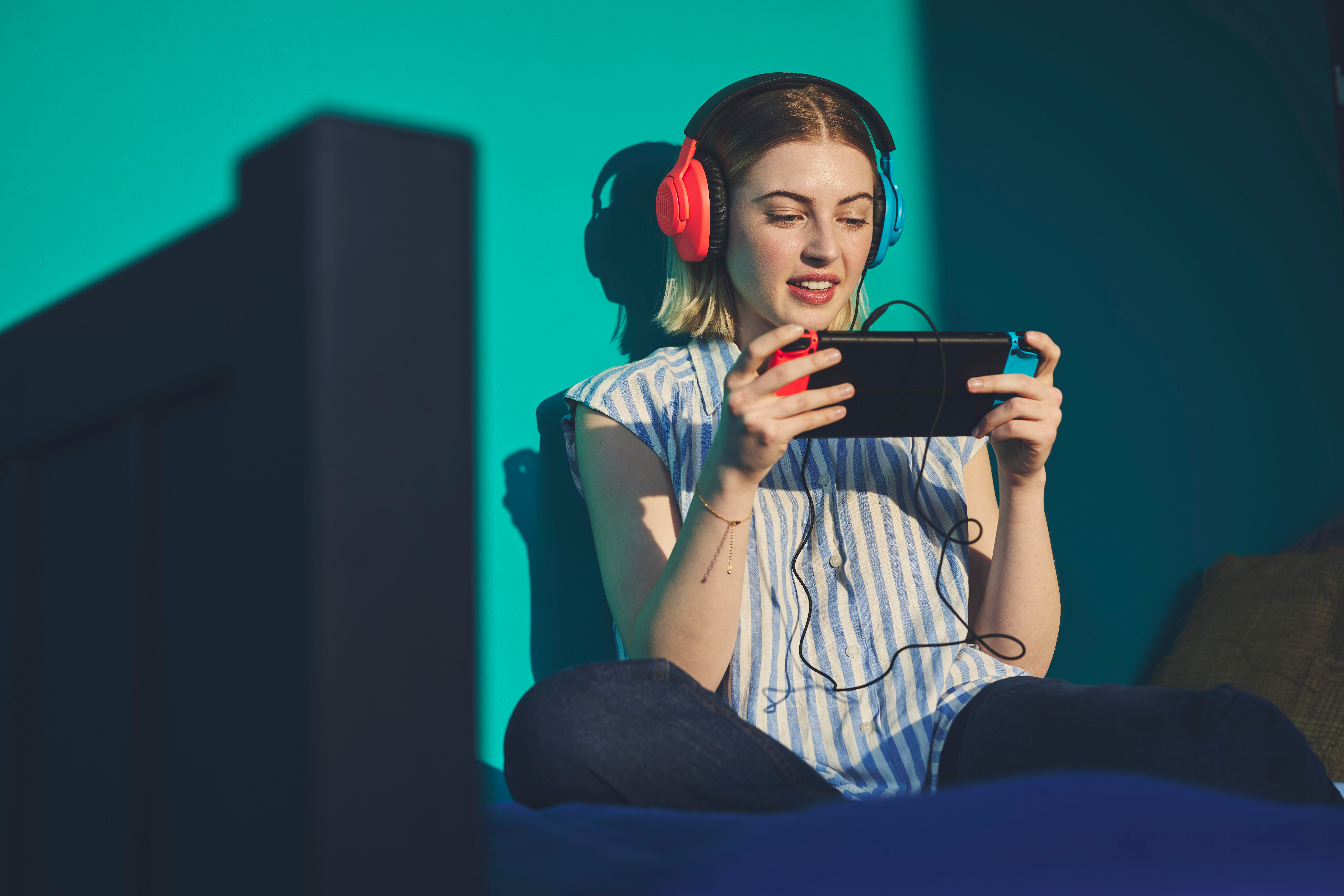 Frau spielt Spiel mit Kopfhörern, hält Switch-Konsole und Controller.