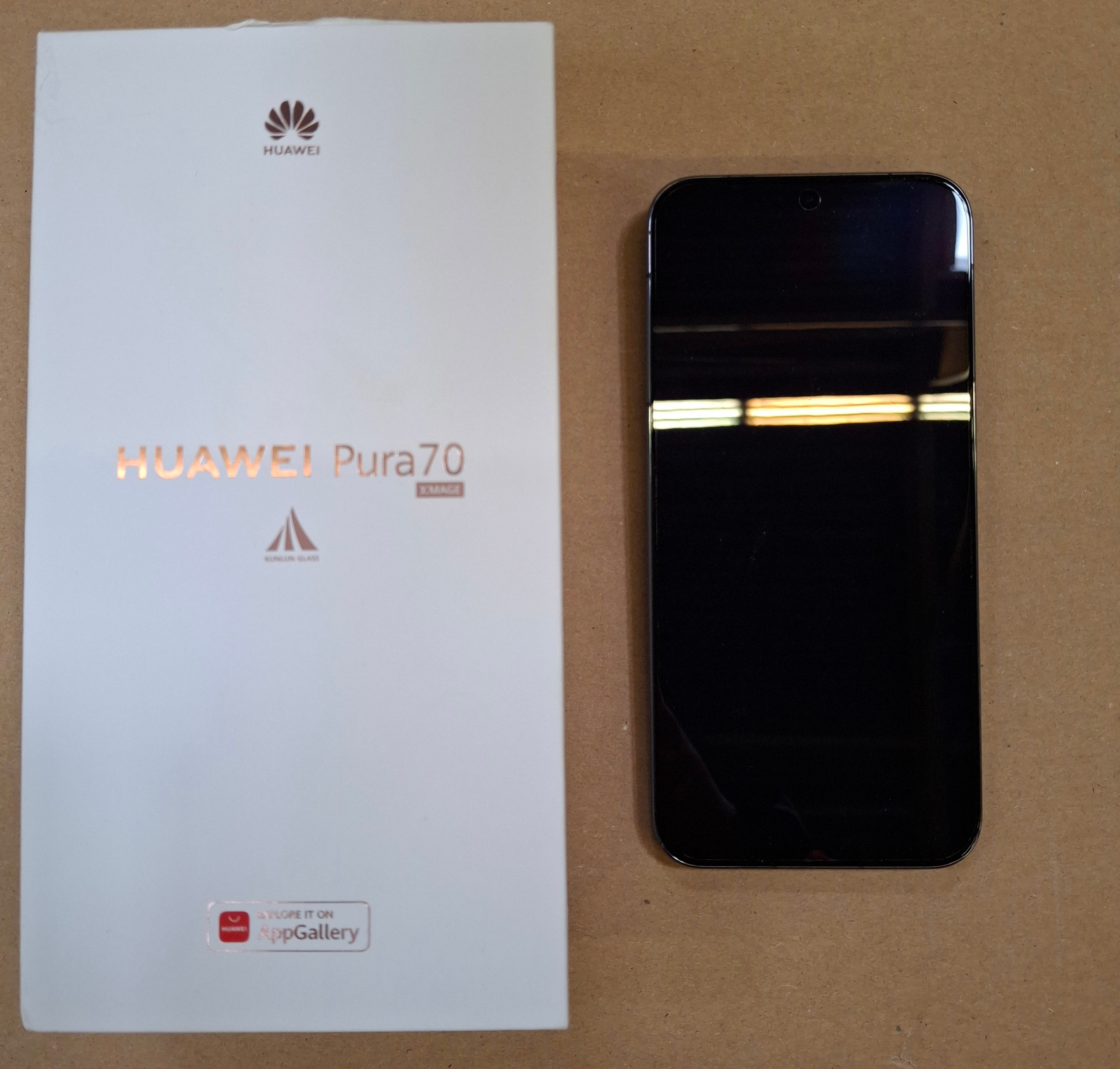 Białe pudełko i czarny telefon. Pudełko mówi HUAWEI Pura70 z telefonem obok.