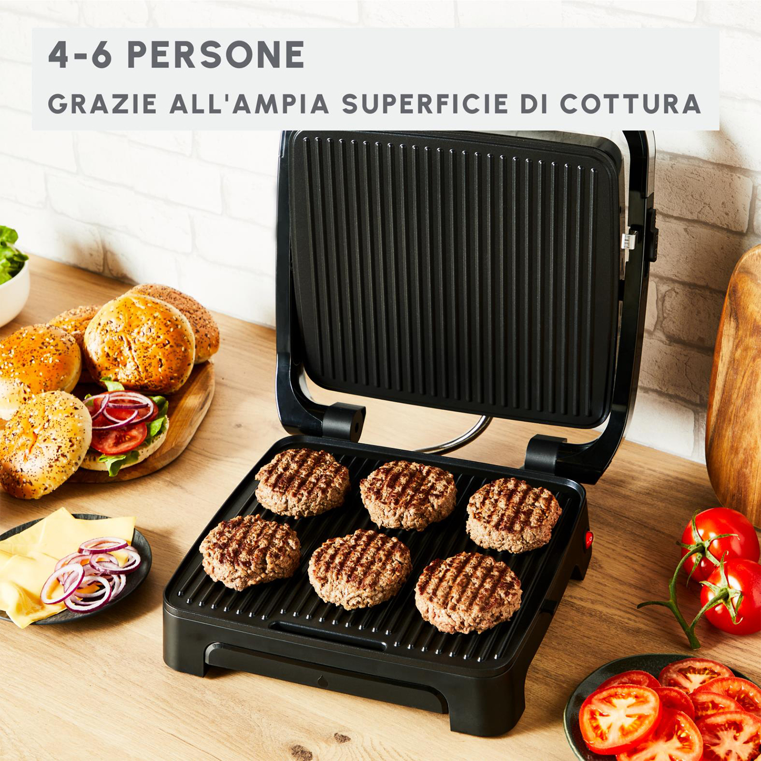 Una griglia con polpette di hamburger cotte. Panini per hamburger, formaggio, pomodori e cipolle sul tavolo.