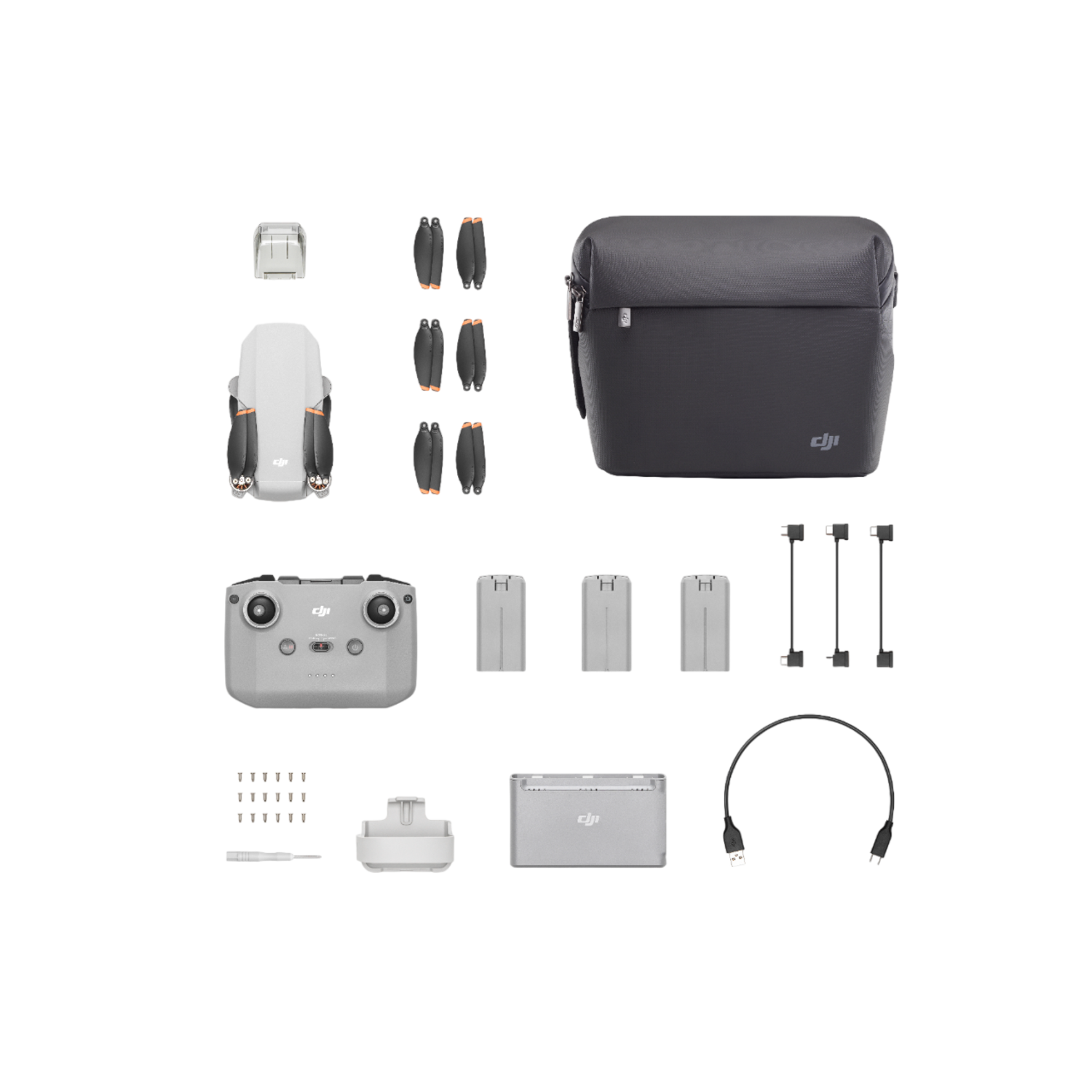 Drone kit: drone, afstandsbediening, batterijen, oplader, kabels en tas. Zwarte achtergrond.