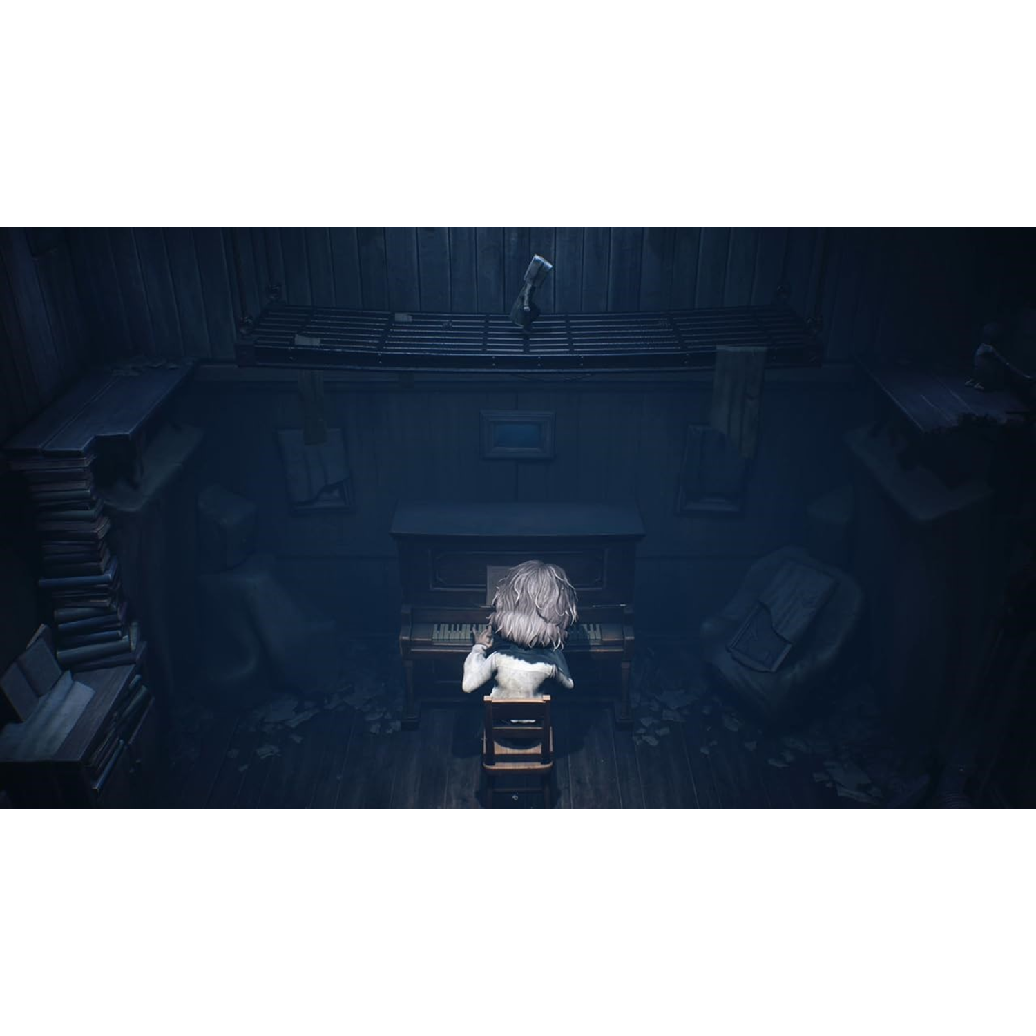A young person playing piano in a dimly lit room. A toy is hanging from the ceiling.