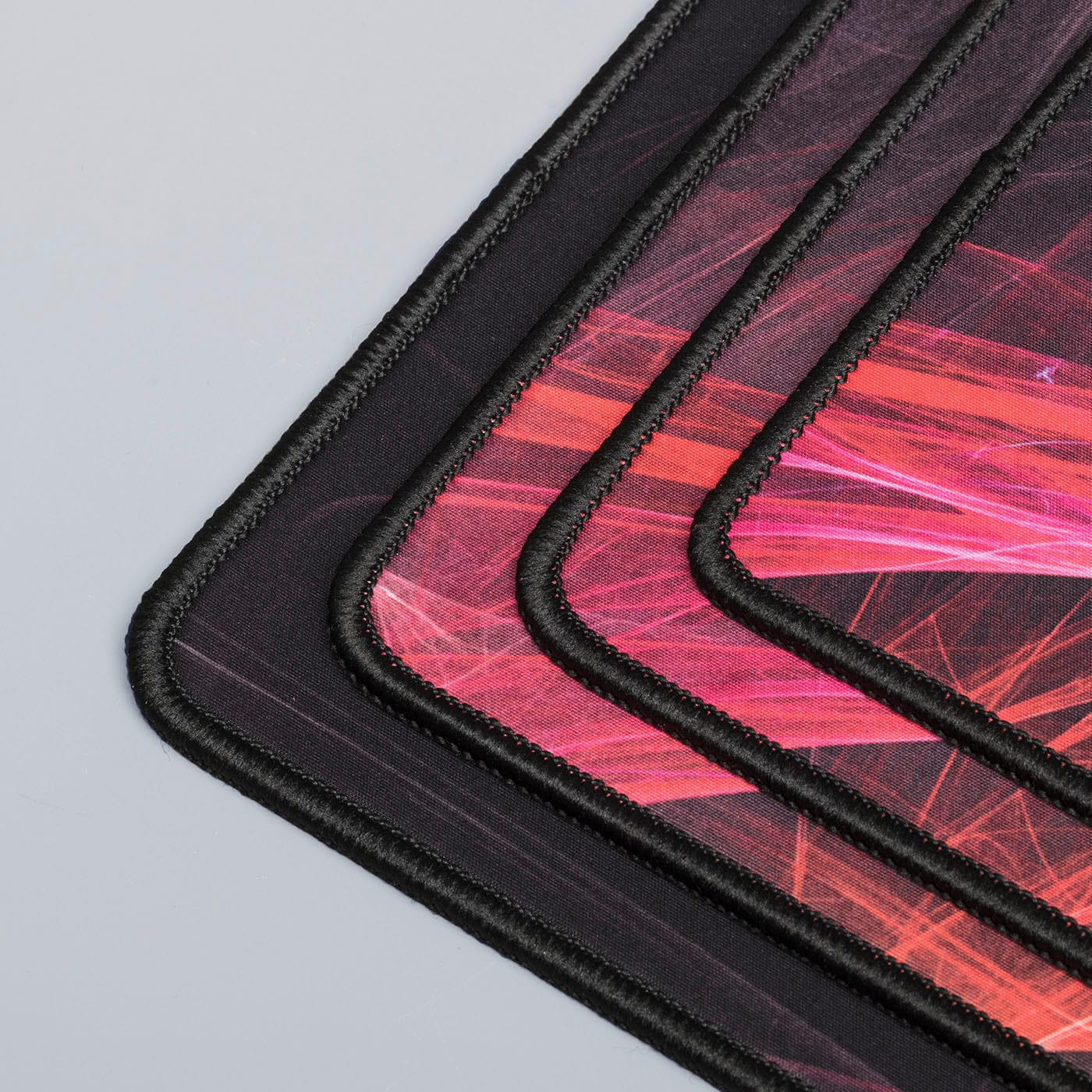 Vier Gaming-Mauspads gestapelt, mit einem roten und schwarzen Design.
