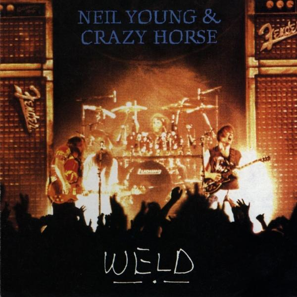 Albumcover von Neil Young & Crazy Horse mit dem Titel 'Weld'. Band spielt live auf der Bühne mit Fans unten.